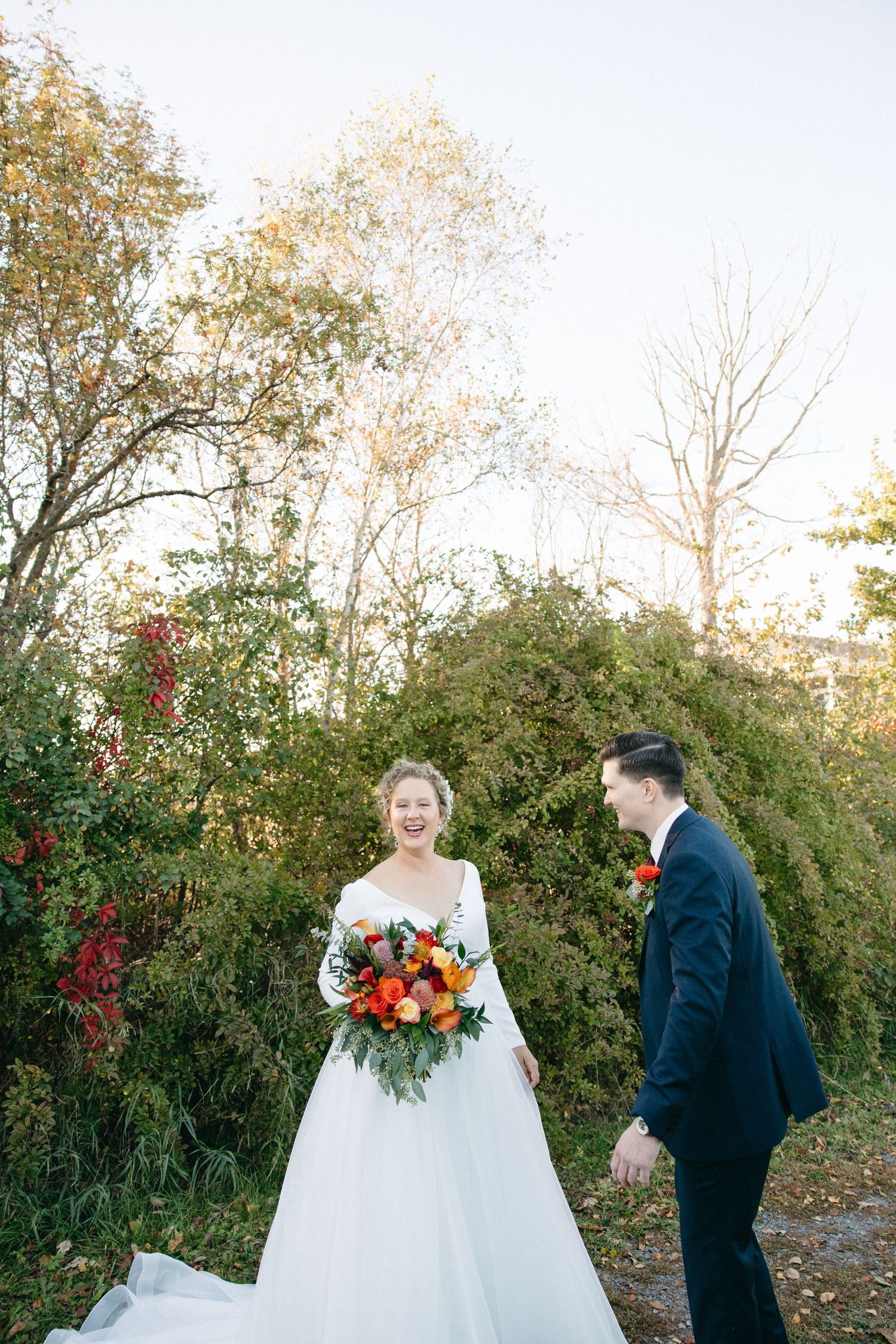A romantic first look wedding sequence with fall foliage and vibrant orange bouquet.