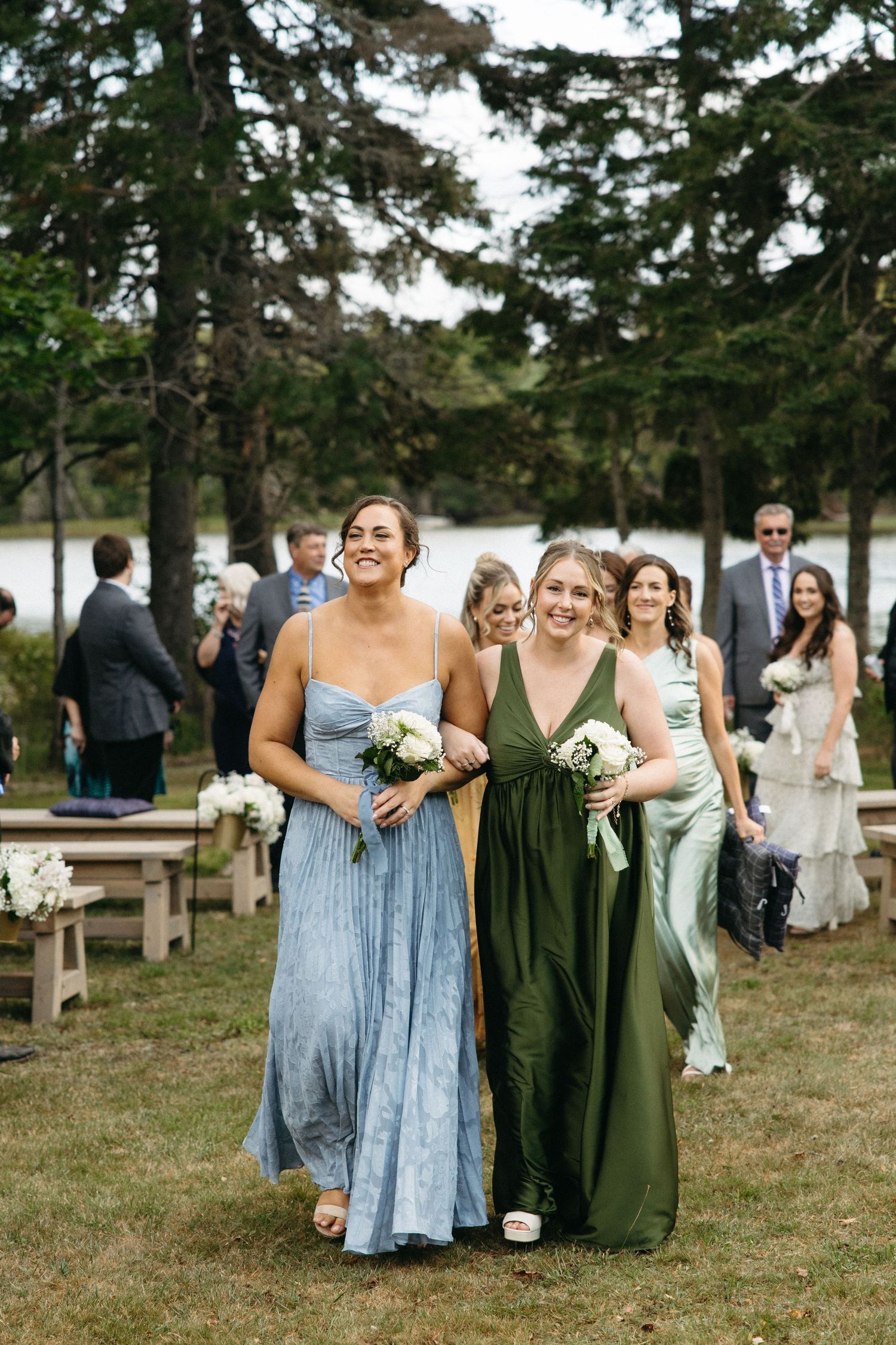 Wedding party members in blue and green dresses walking together outdoors.