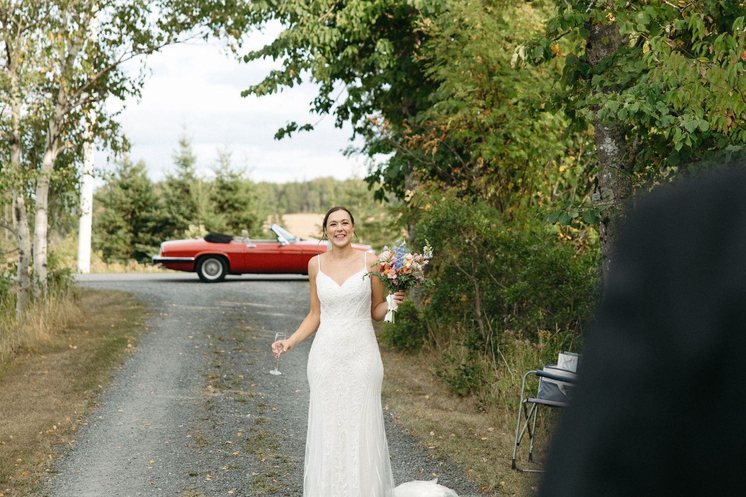 Wedding couple posing on a rural dirt road surrounded by trees.