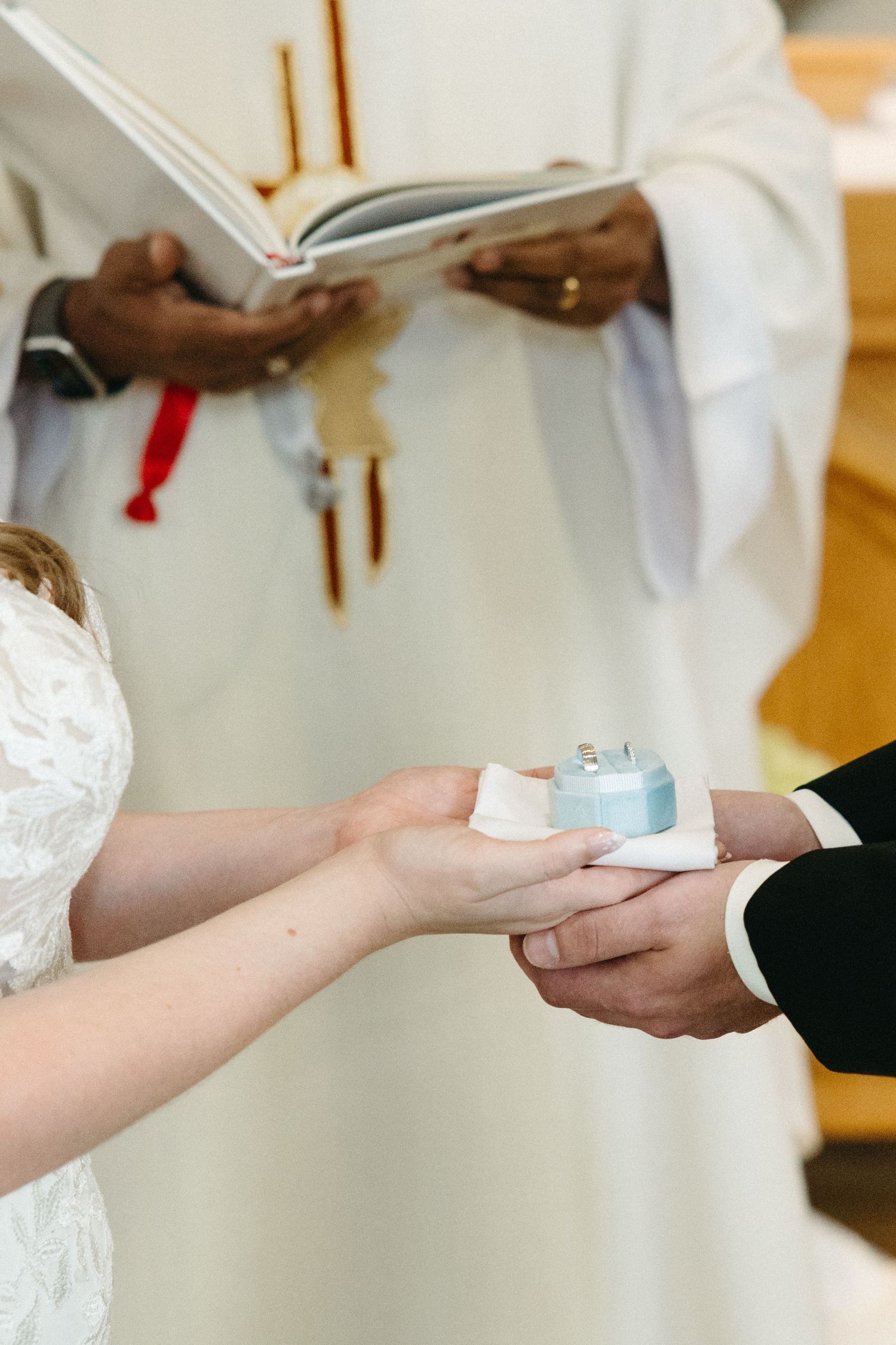 Close-up of hands exchanging wedding rings during a church ceremony.