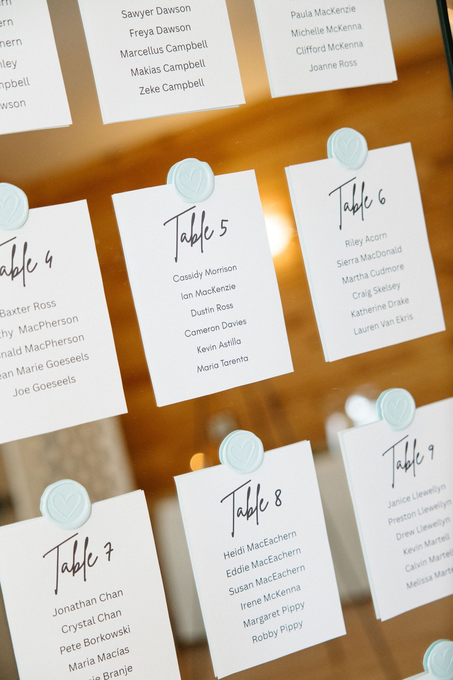 Minimalist wedding seating chart with table numbers and guest names on white cards.