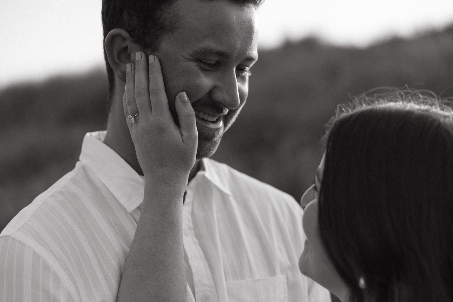 Black and white portrait of a couple sharing an intimate moment outdoors.