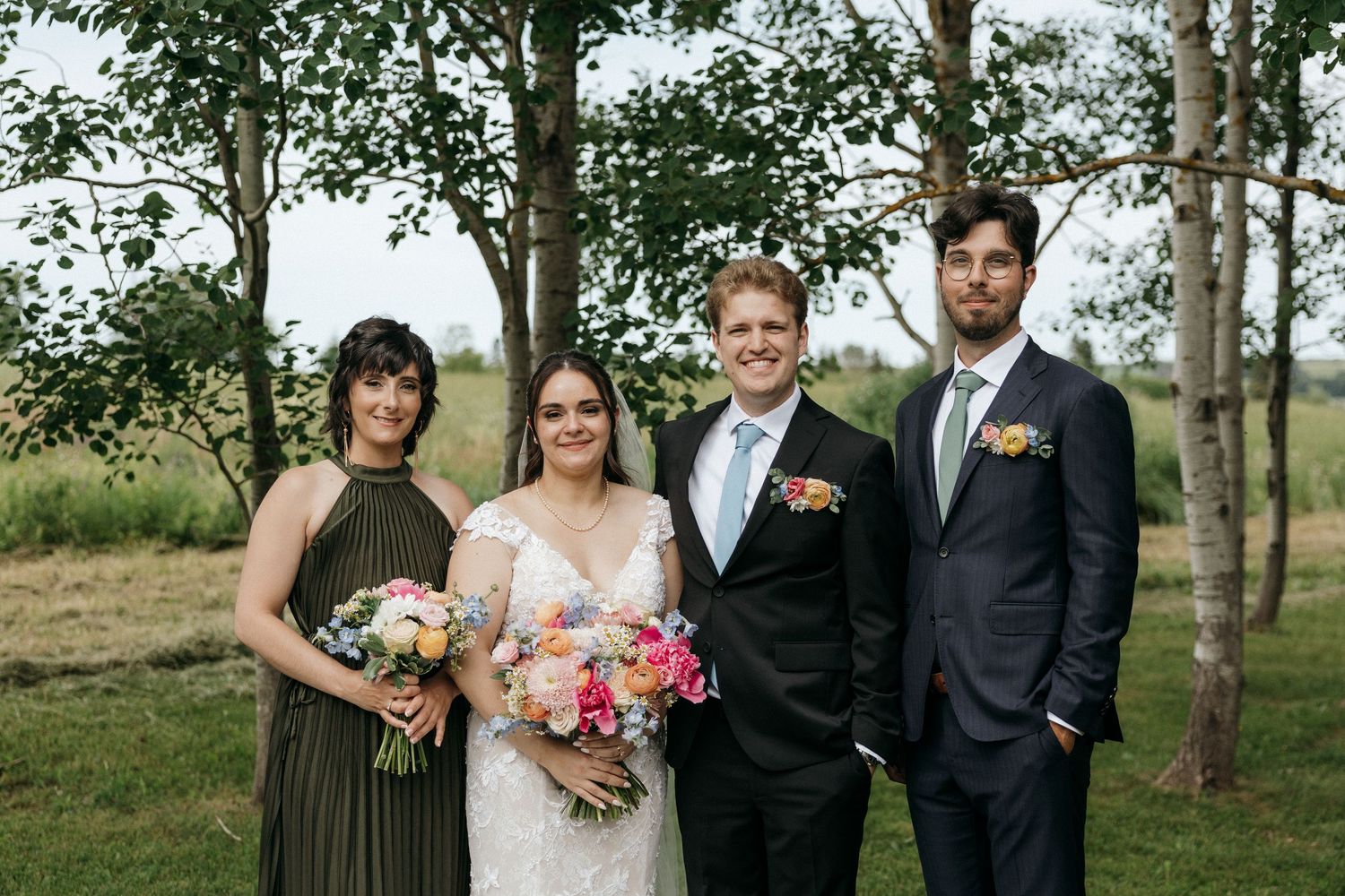 Wedding party posed among birch trees in an outdoor setting.