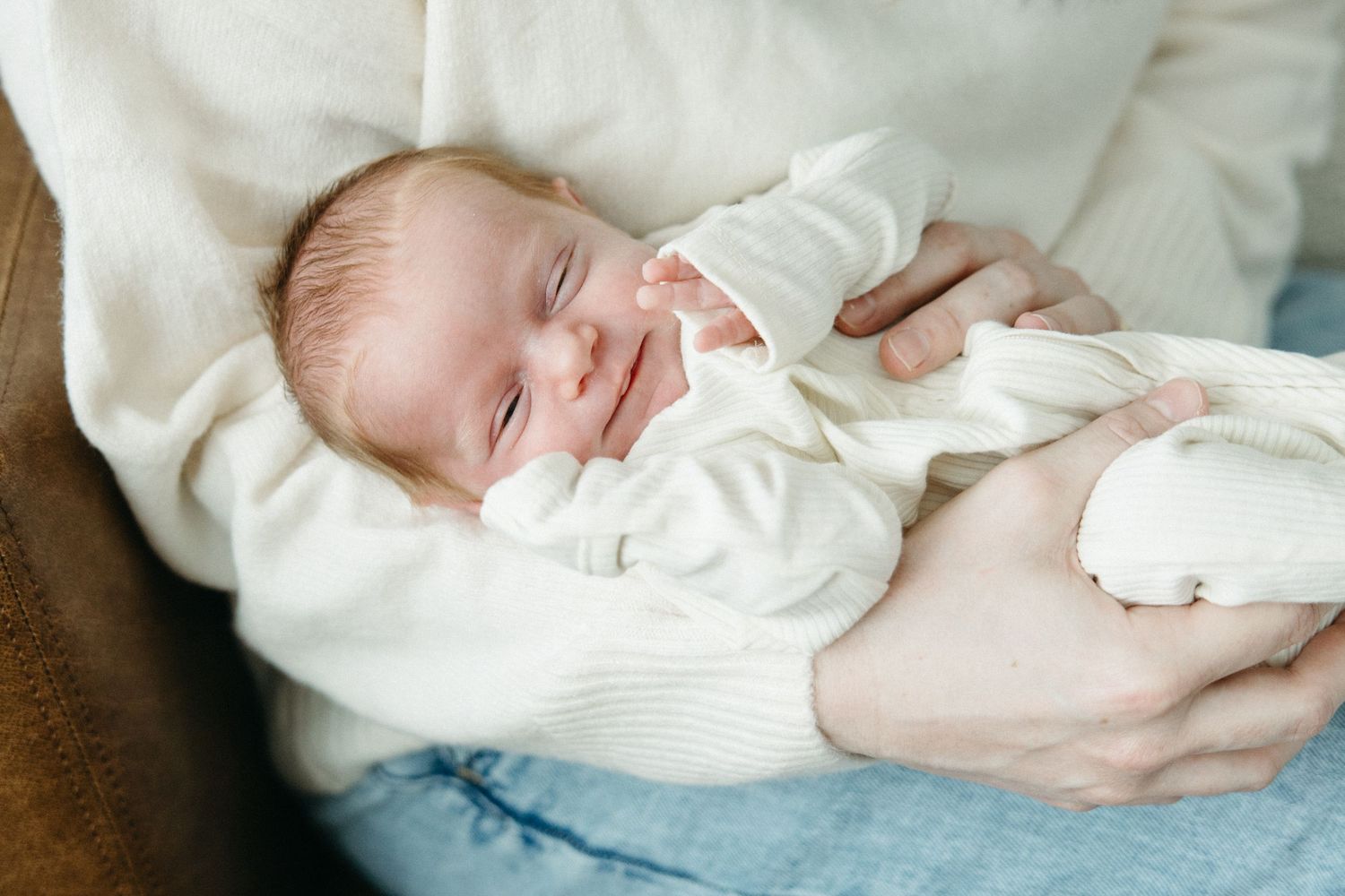 A sleeping baby in white clothing lies peacefully on soft blue bedding.