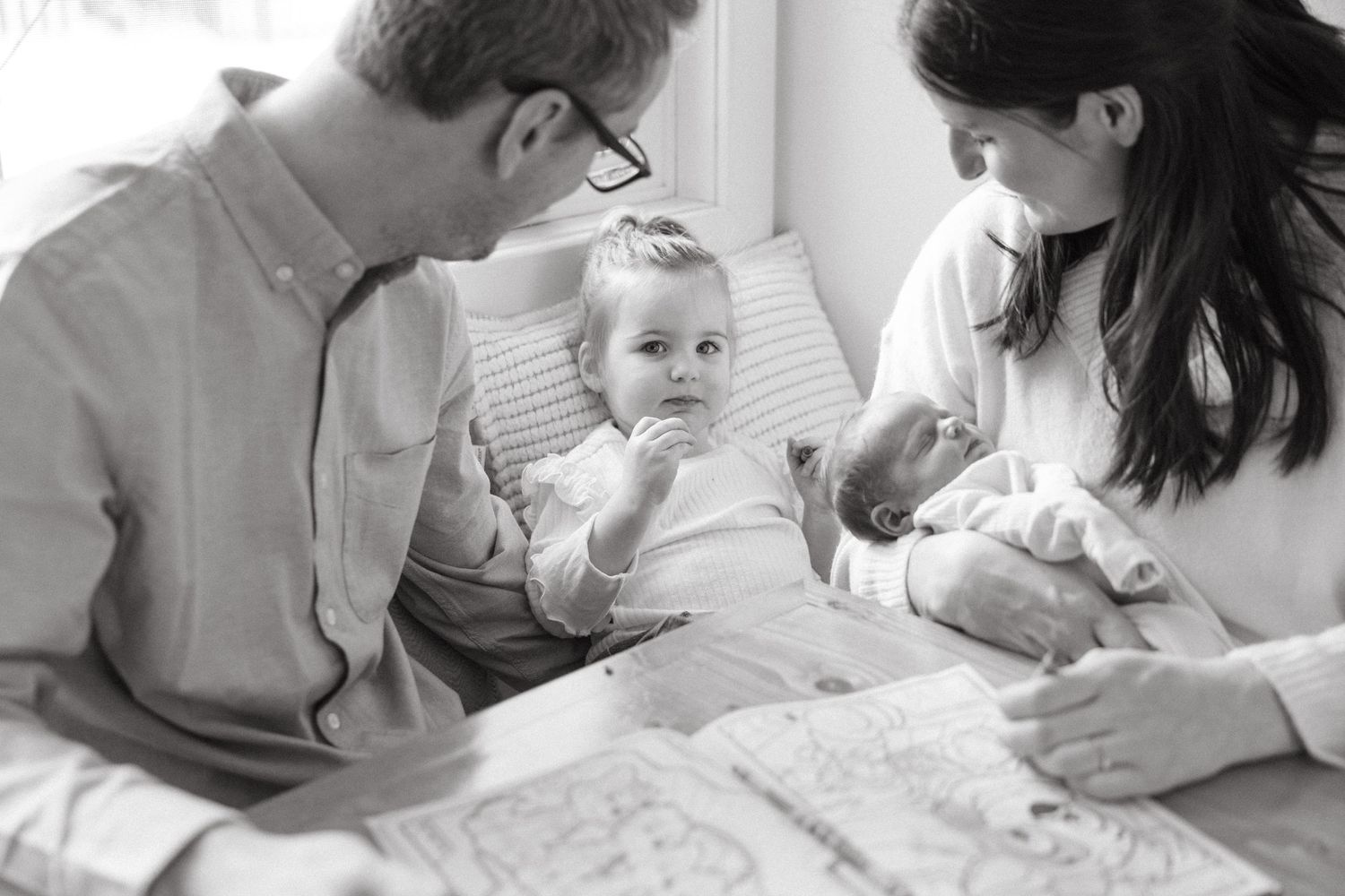 An intimate black and white photo captures a family moment at the table.