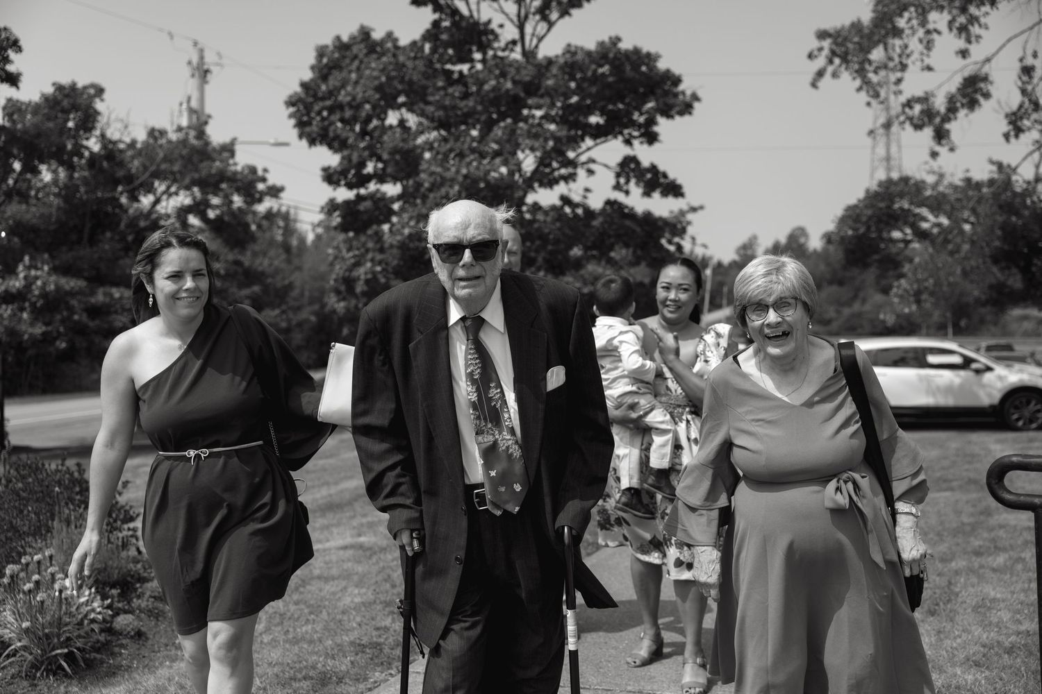 Wedding guests gathered outdoors on a sunny summer day.