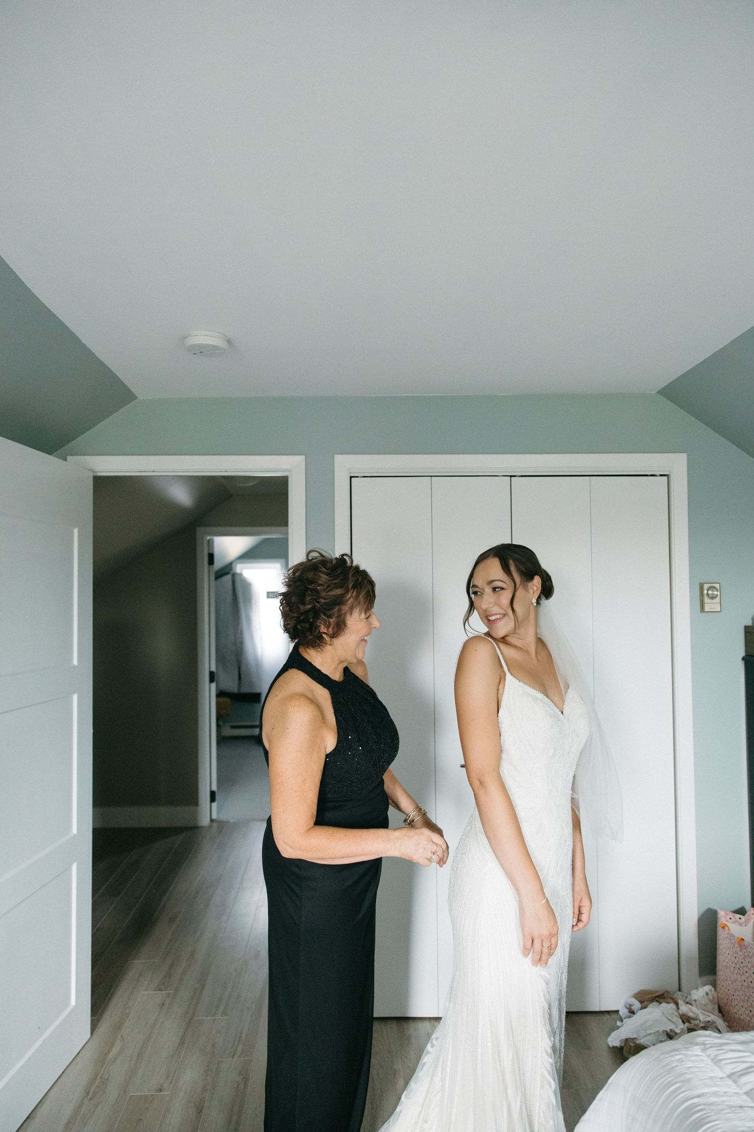 Wedding dress preparation scene in bright modern room with white doors.