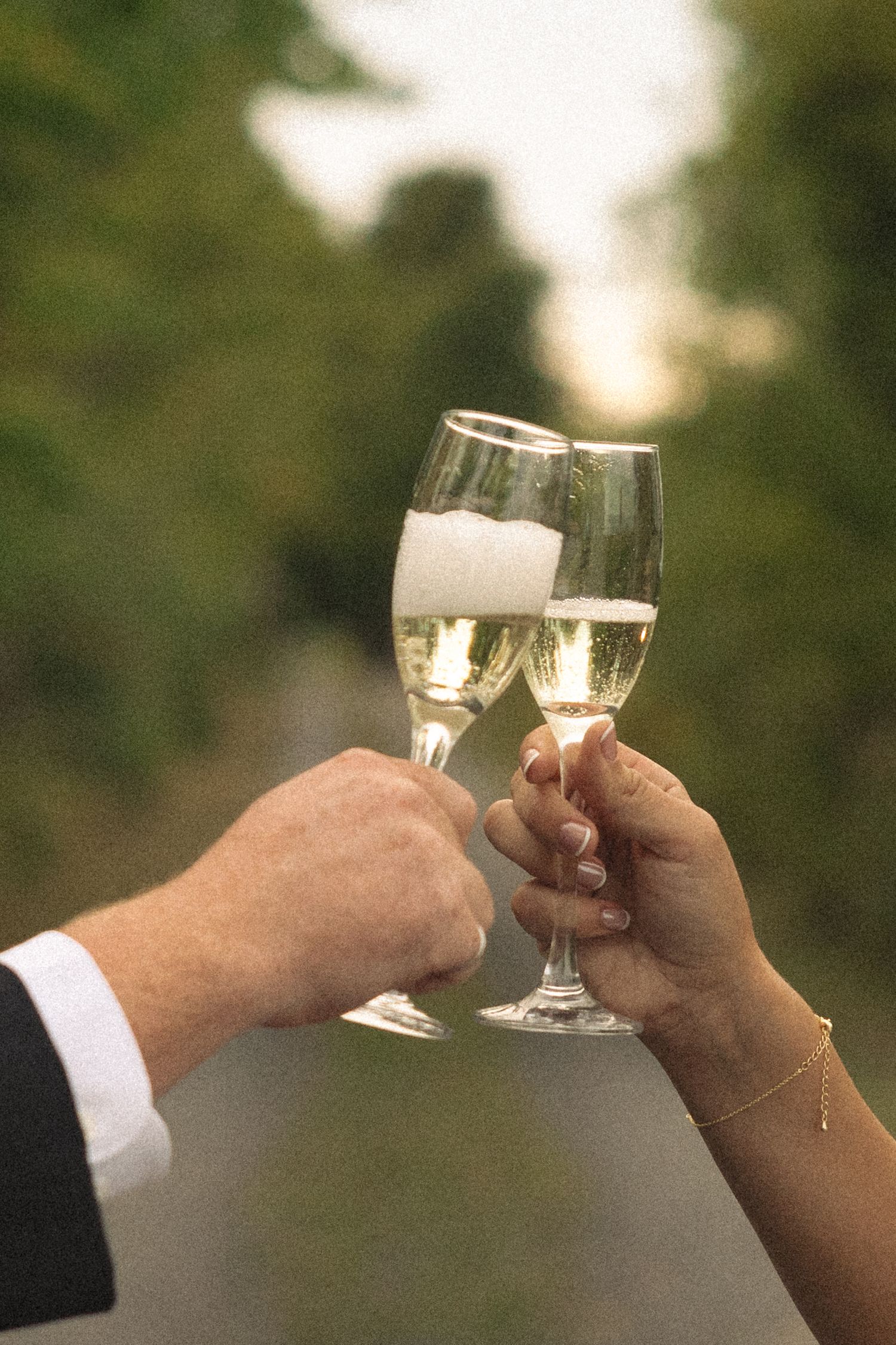 Close-up of hands toasting with champagne glasses during a wedding celebration.