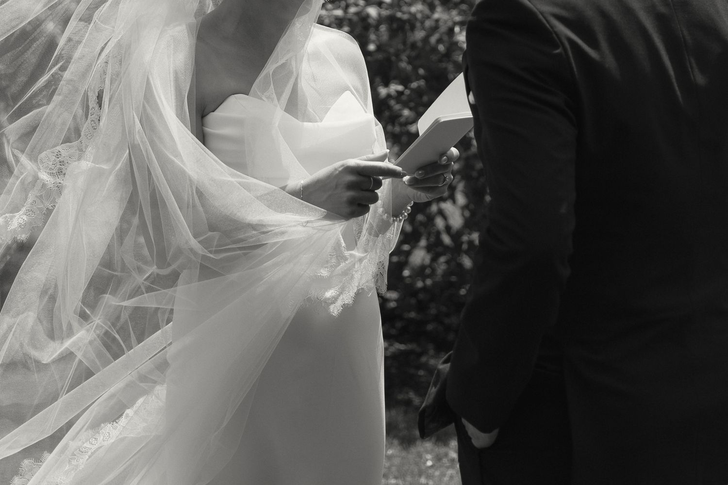 A flowing white wedding veil billows elegantly in the breeze against a dark background.