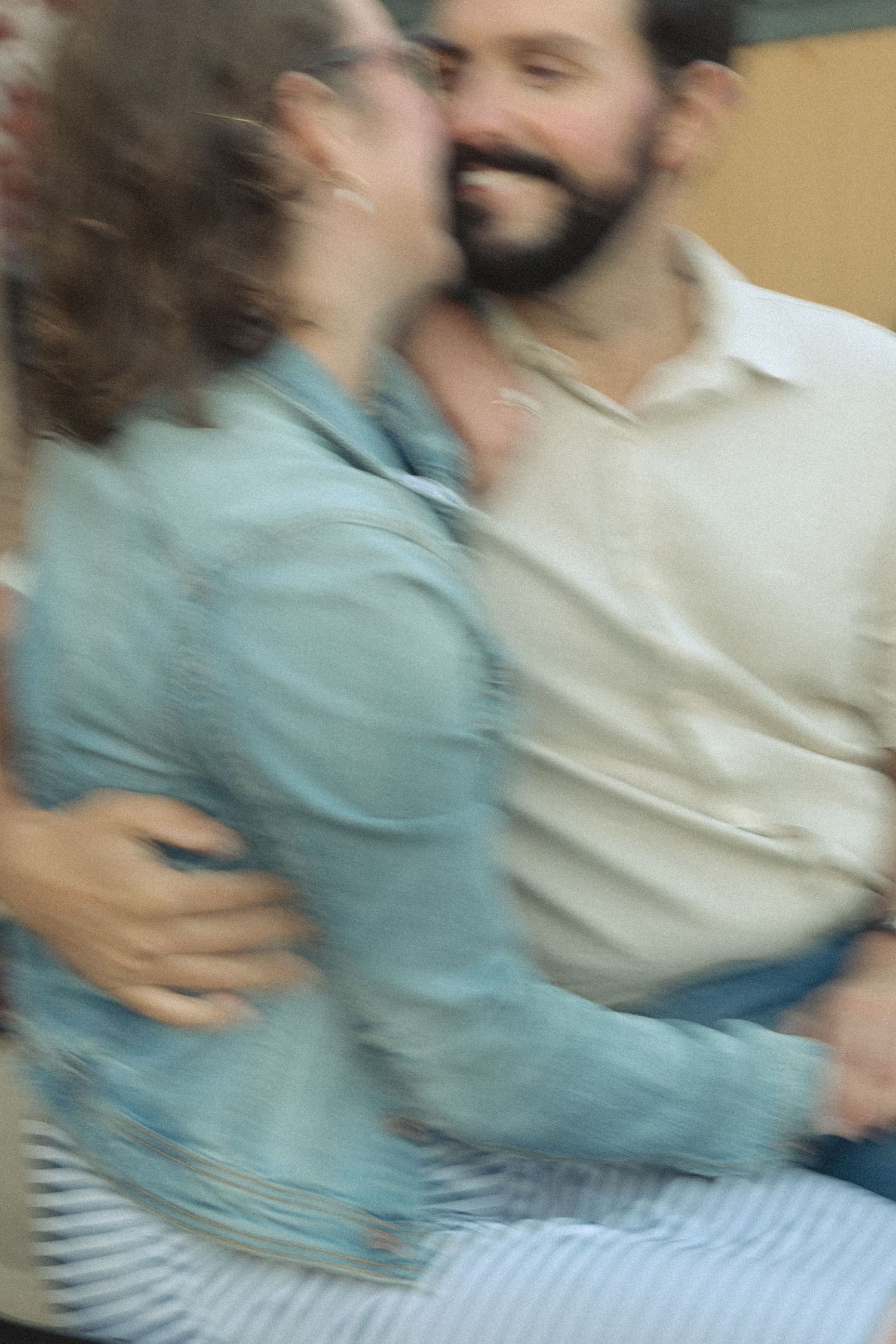 Blurred motion candid shot of two people in casual clothing embracing.
