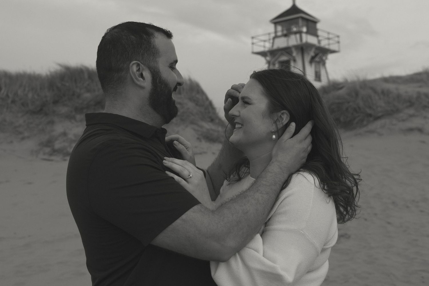 Intimate black and white photos of a couple sharing tender moments on the beach.