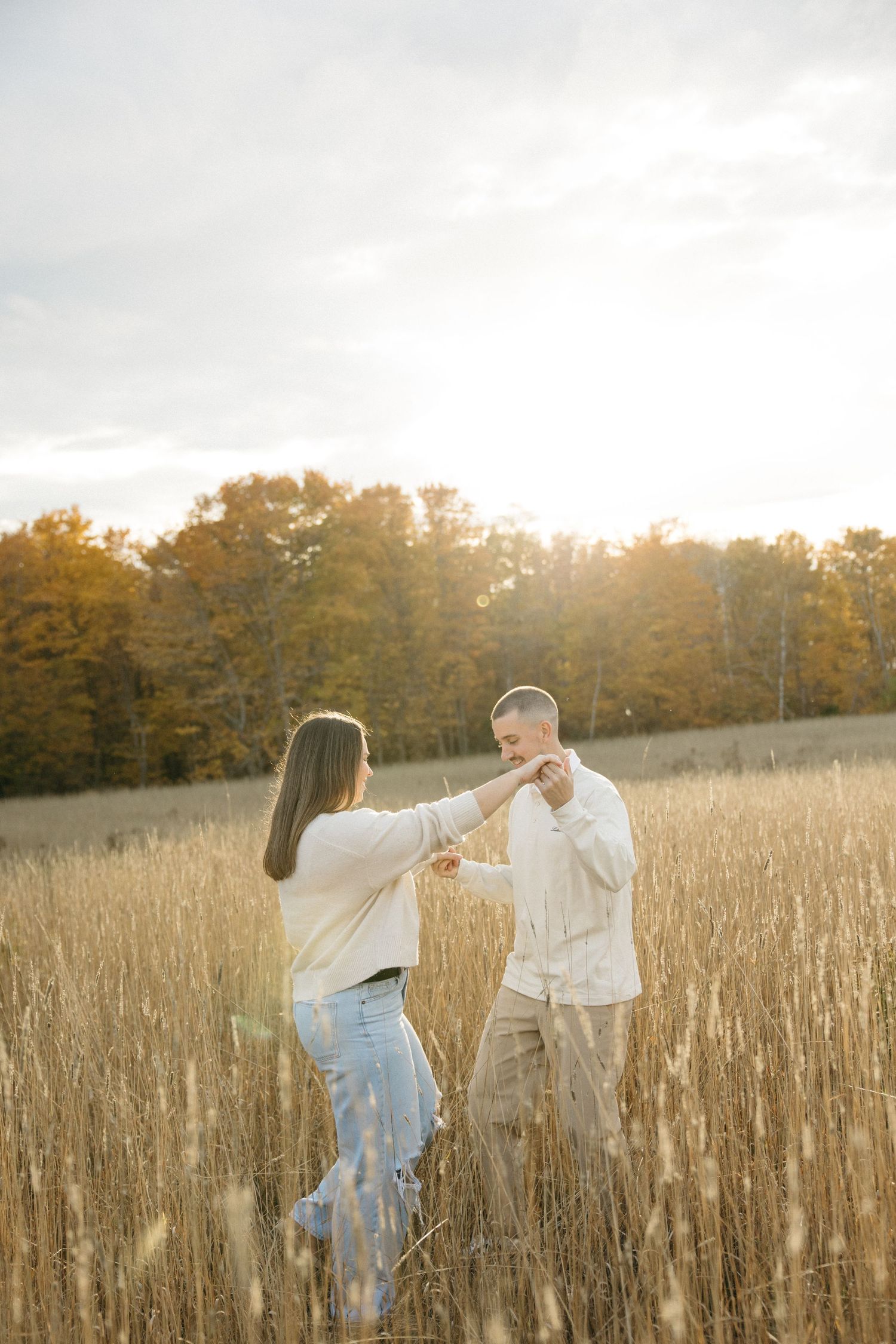 A couple dances and twirls through tall grass at golden hour.