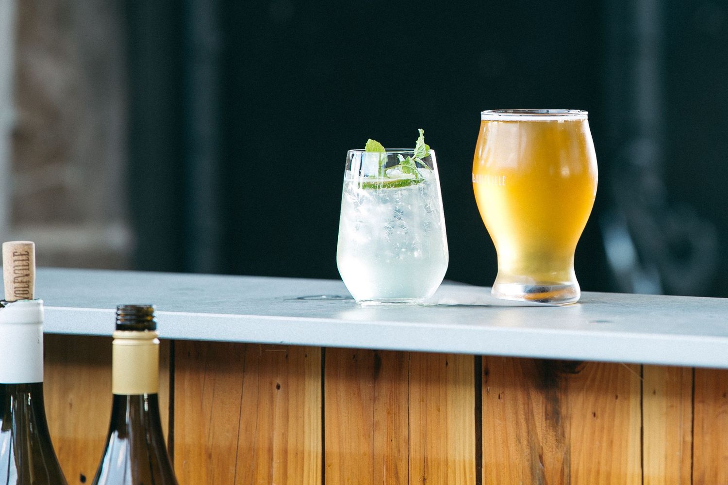 Two drinks on marble bar counter - a beer and cocktail with garnish.