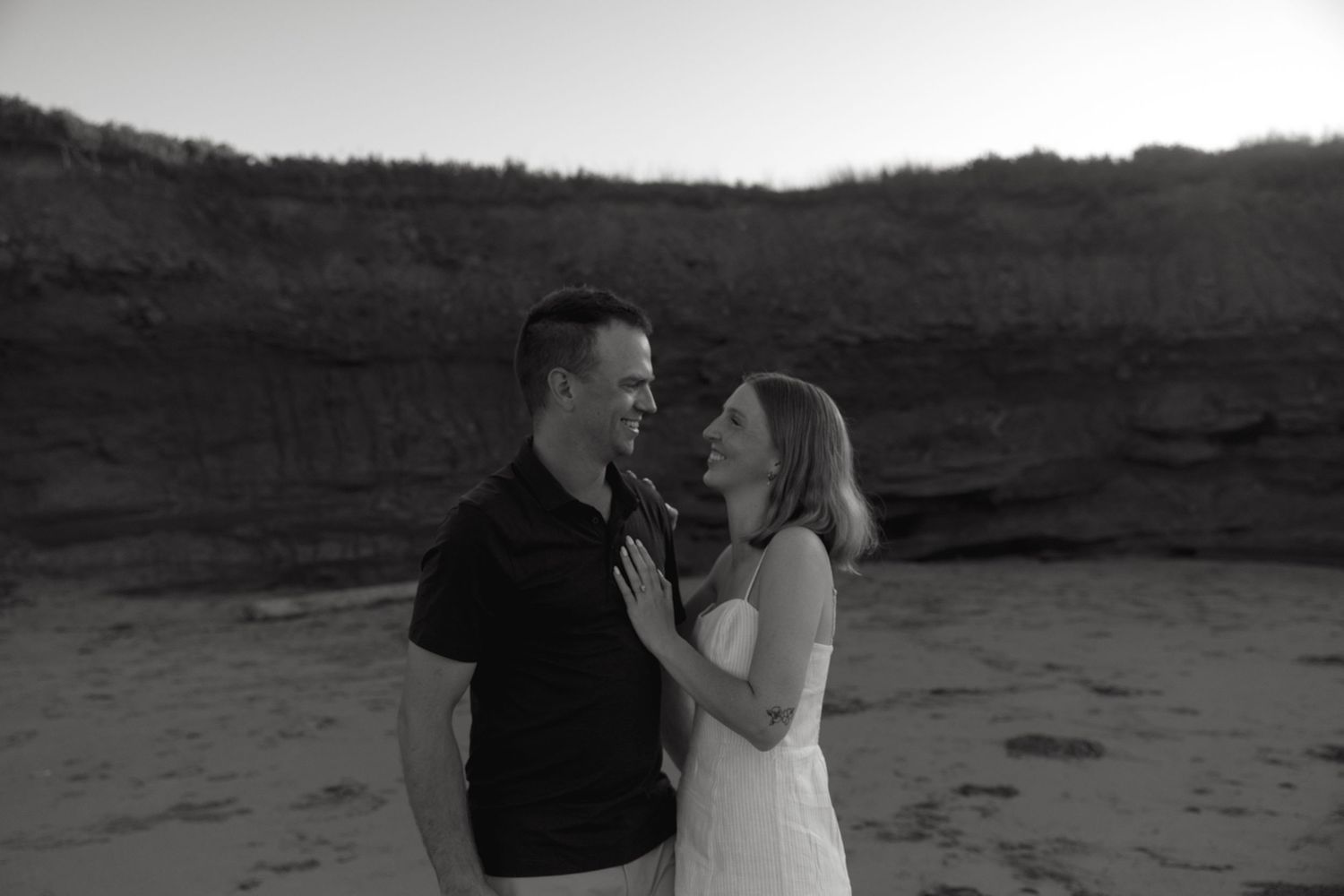 Romantic couple moment captured against beach cliffs at sunset.