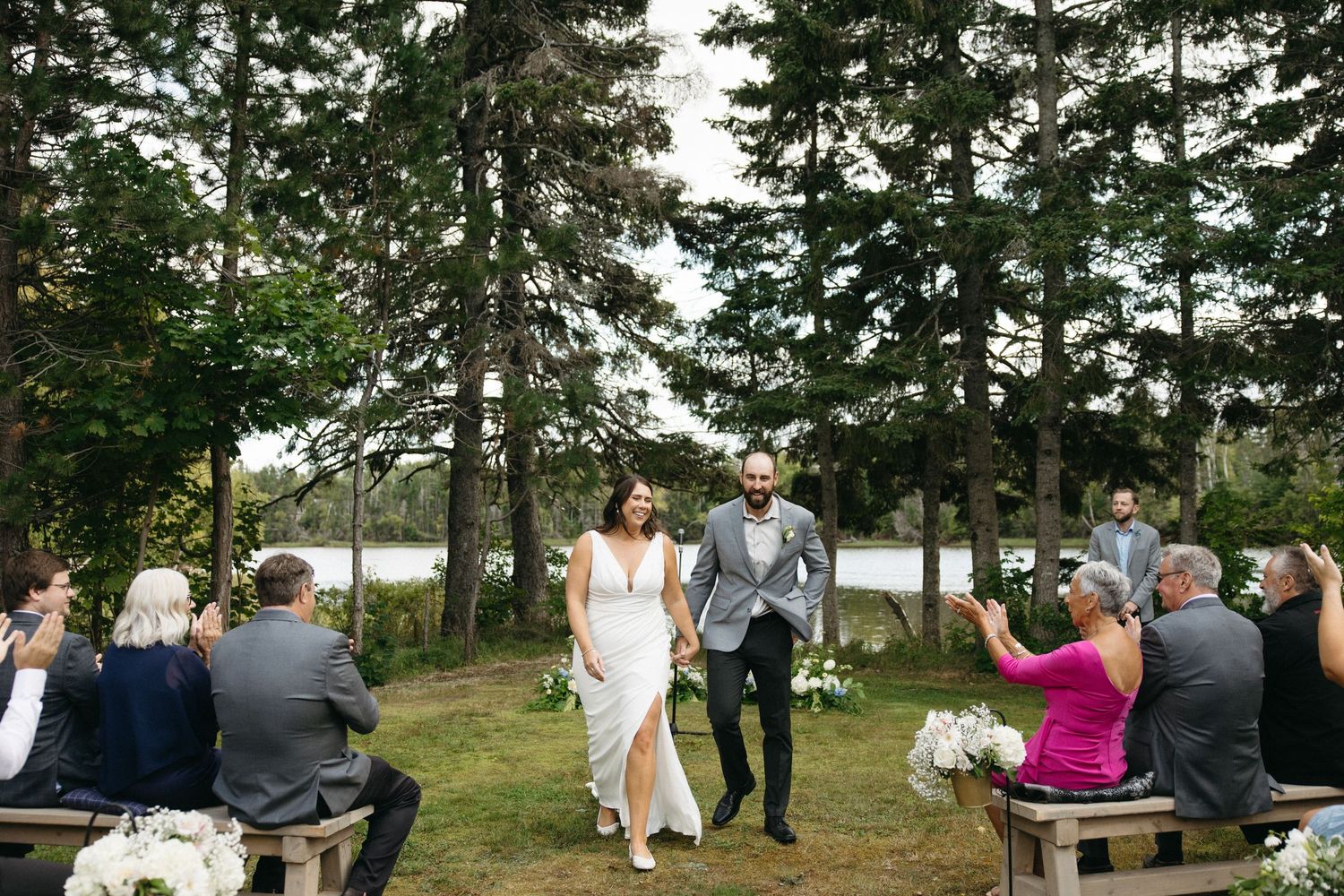 Wedding celebration scene with guests mingling under pine trees.