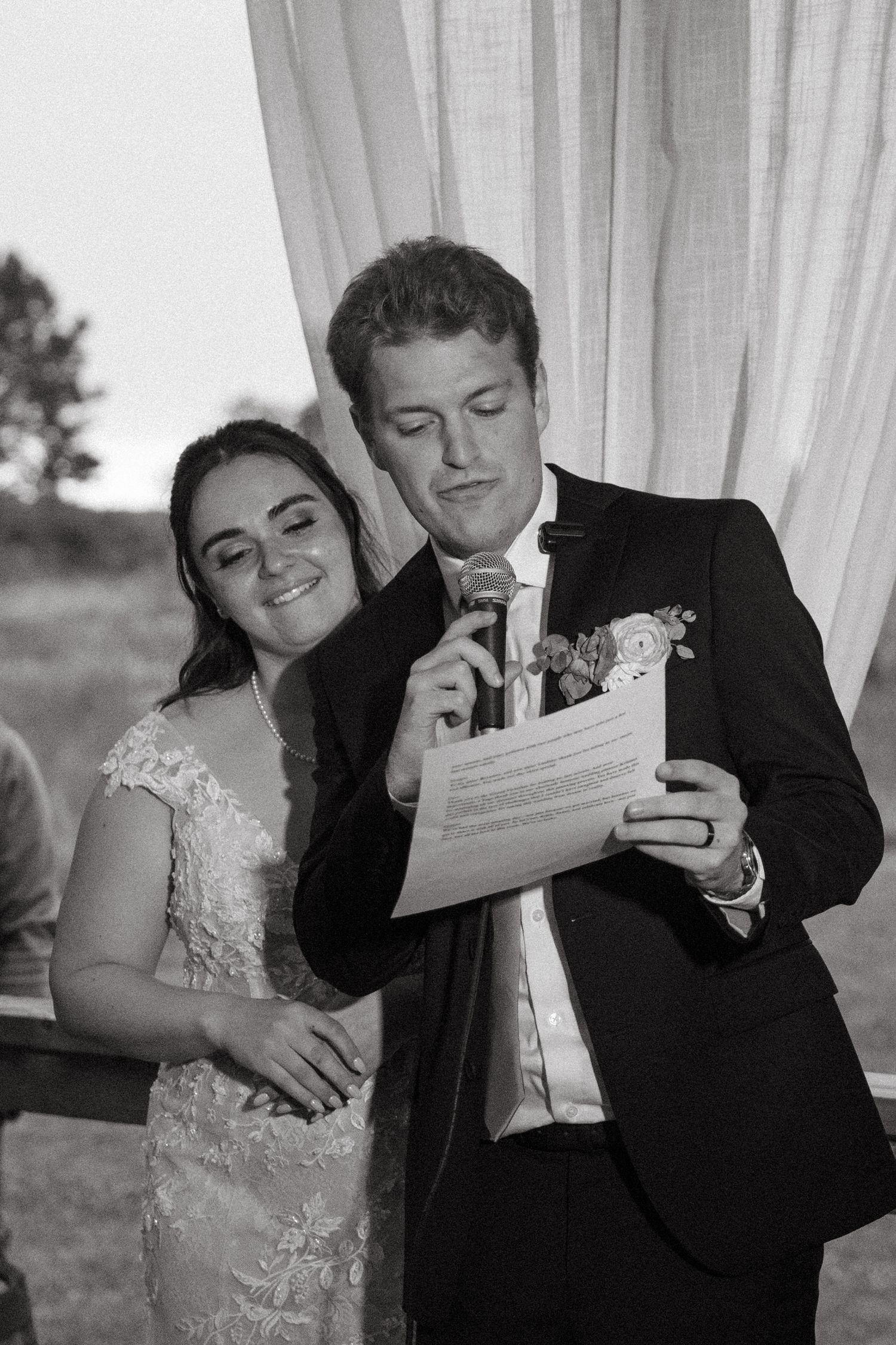 A bride and groom share a joyful moment while reading a document during their wedding ceremony.