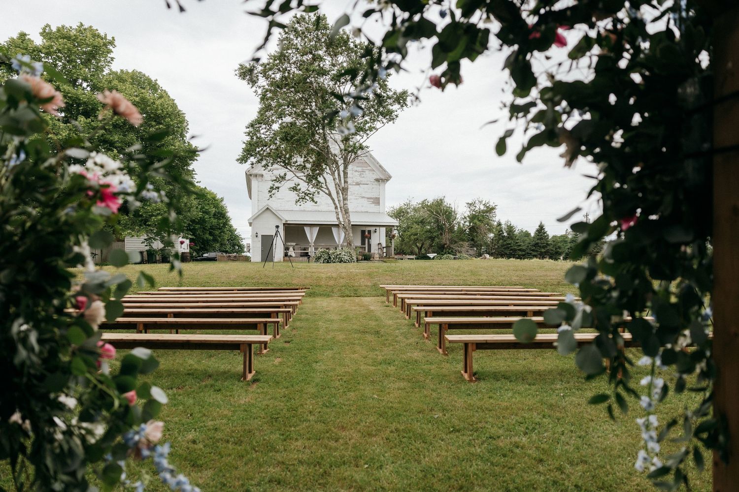 Wooden benches arranged on a grassy hill for an outdoor wedding ceremony.