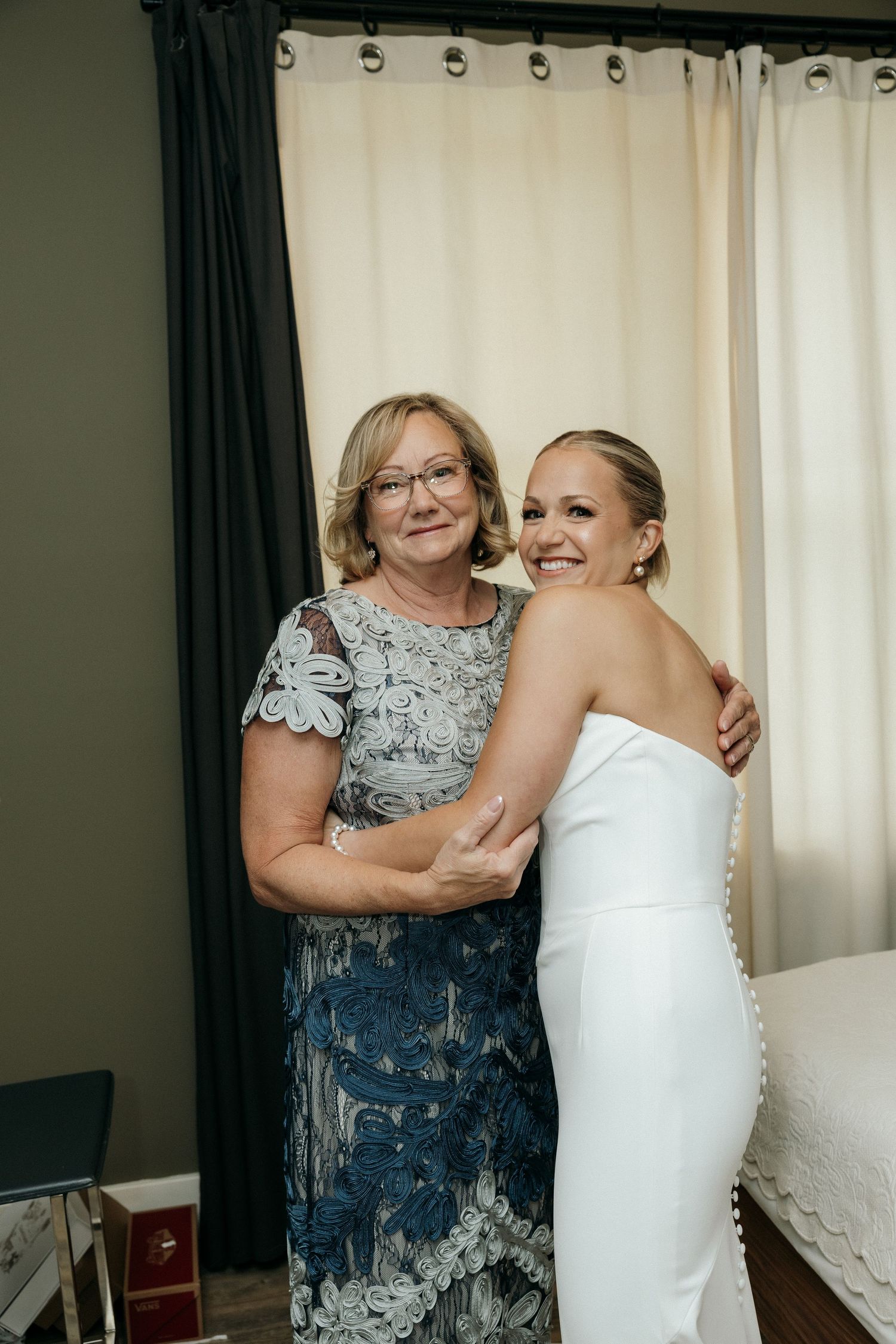Emotional wedding preparation moment in a room with curtains.
