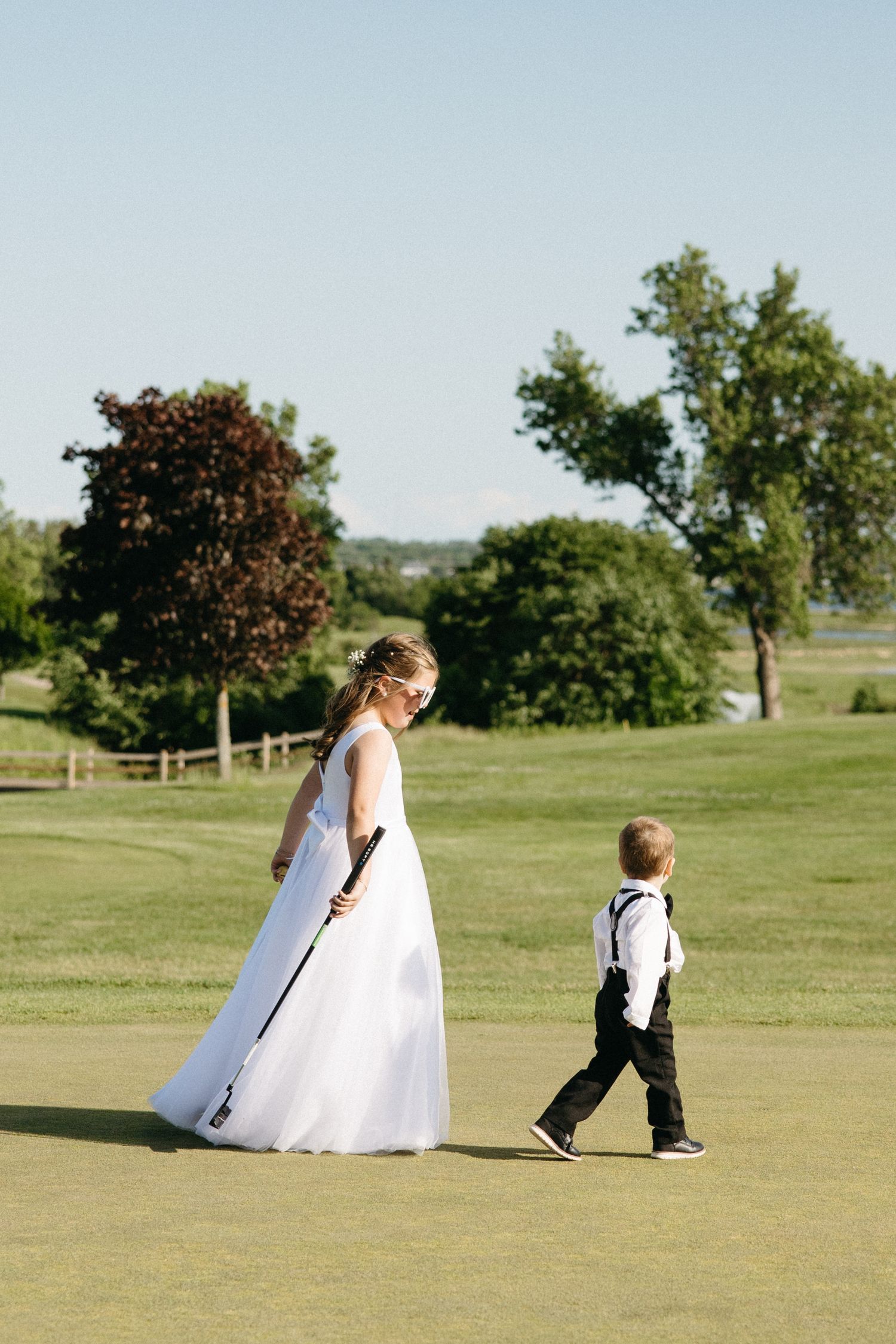 People walking across a sunny green field during an outdoor wedding ceremony.