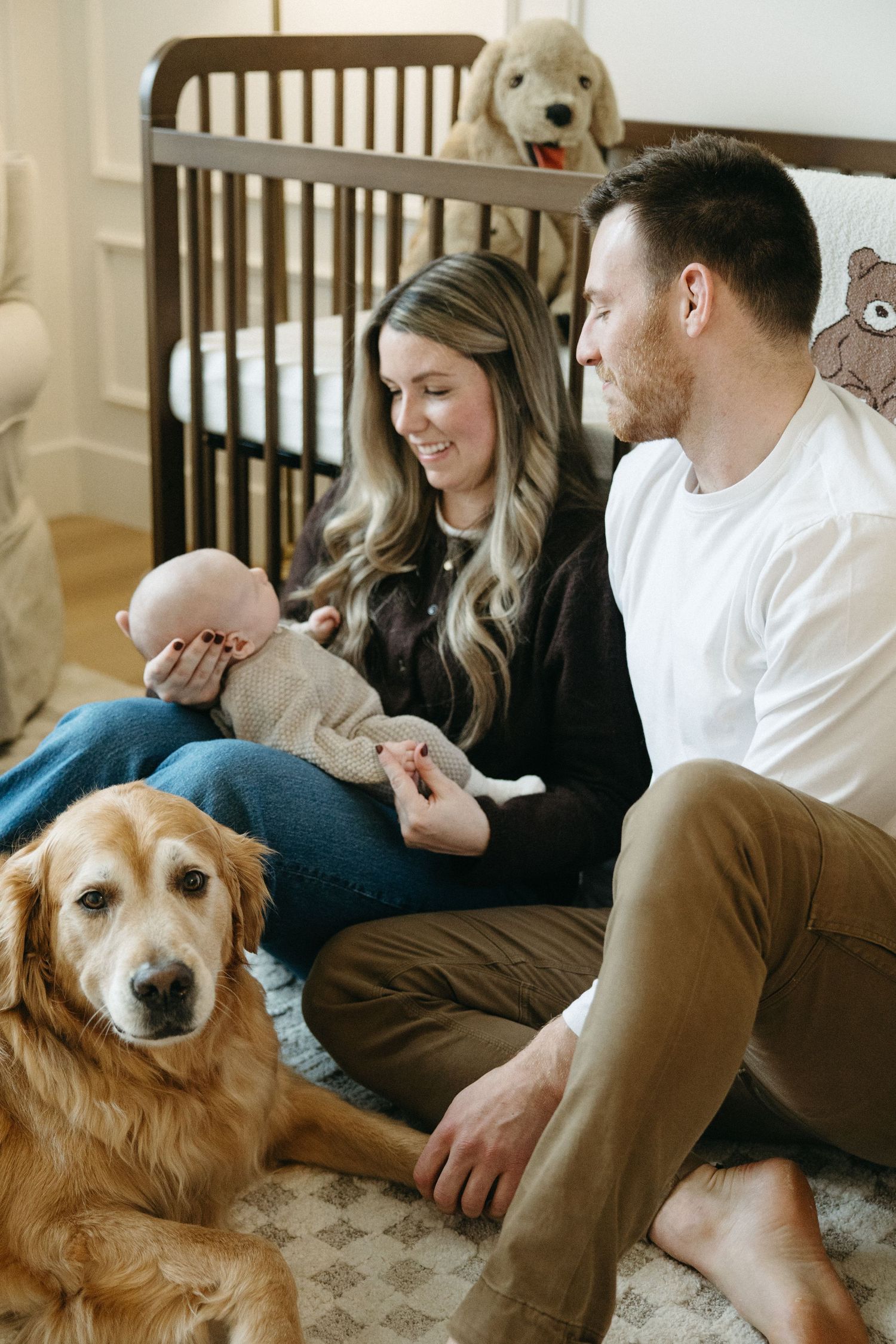 Golden retriever lounging with family on patterned rug in nursery.