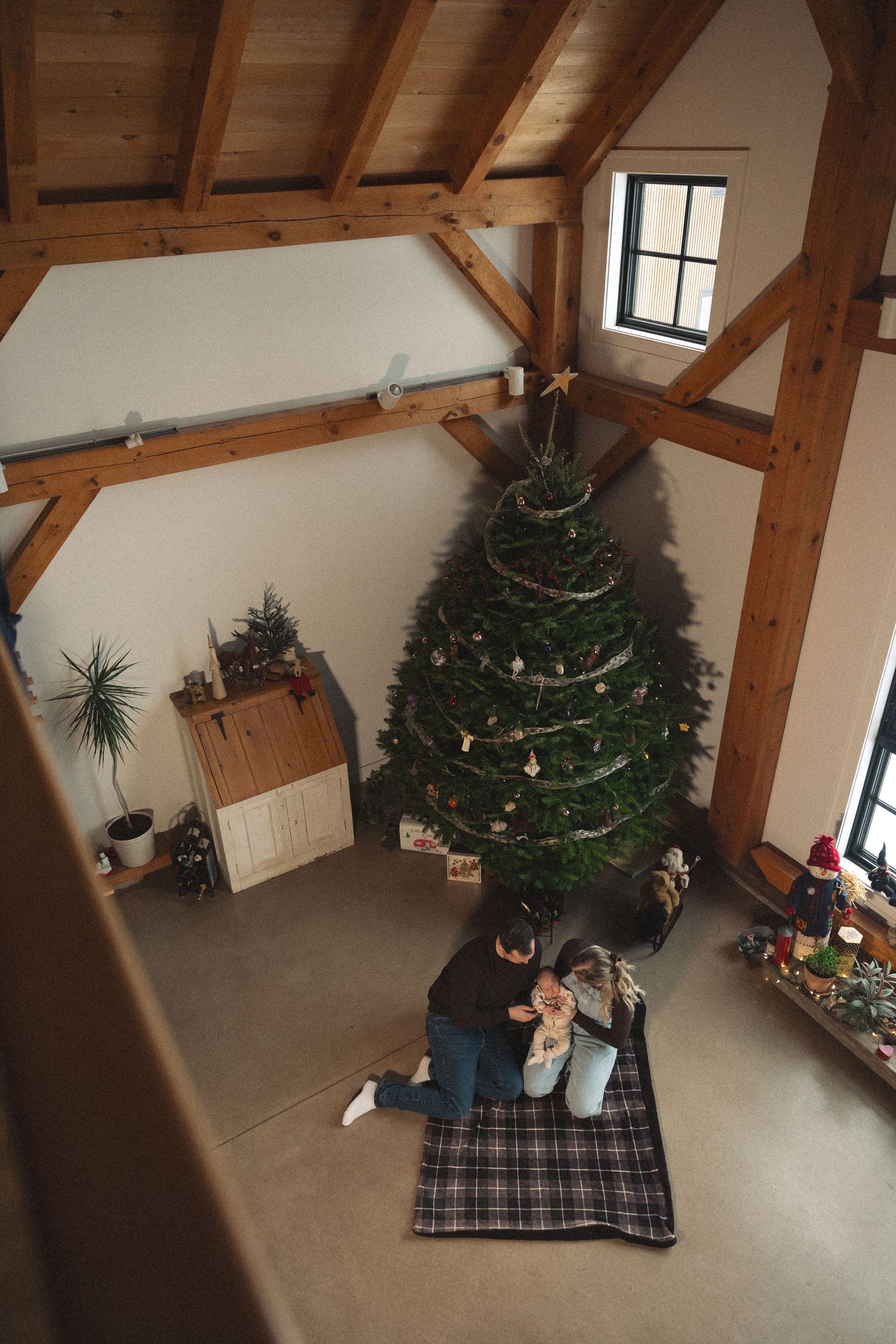 A cozy room with exposed wooden beams and a decorated Christmas tree in the corner.