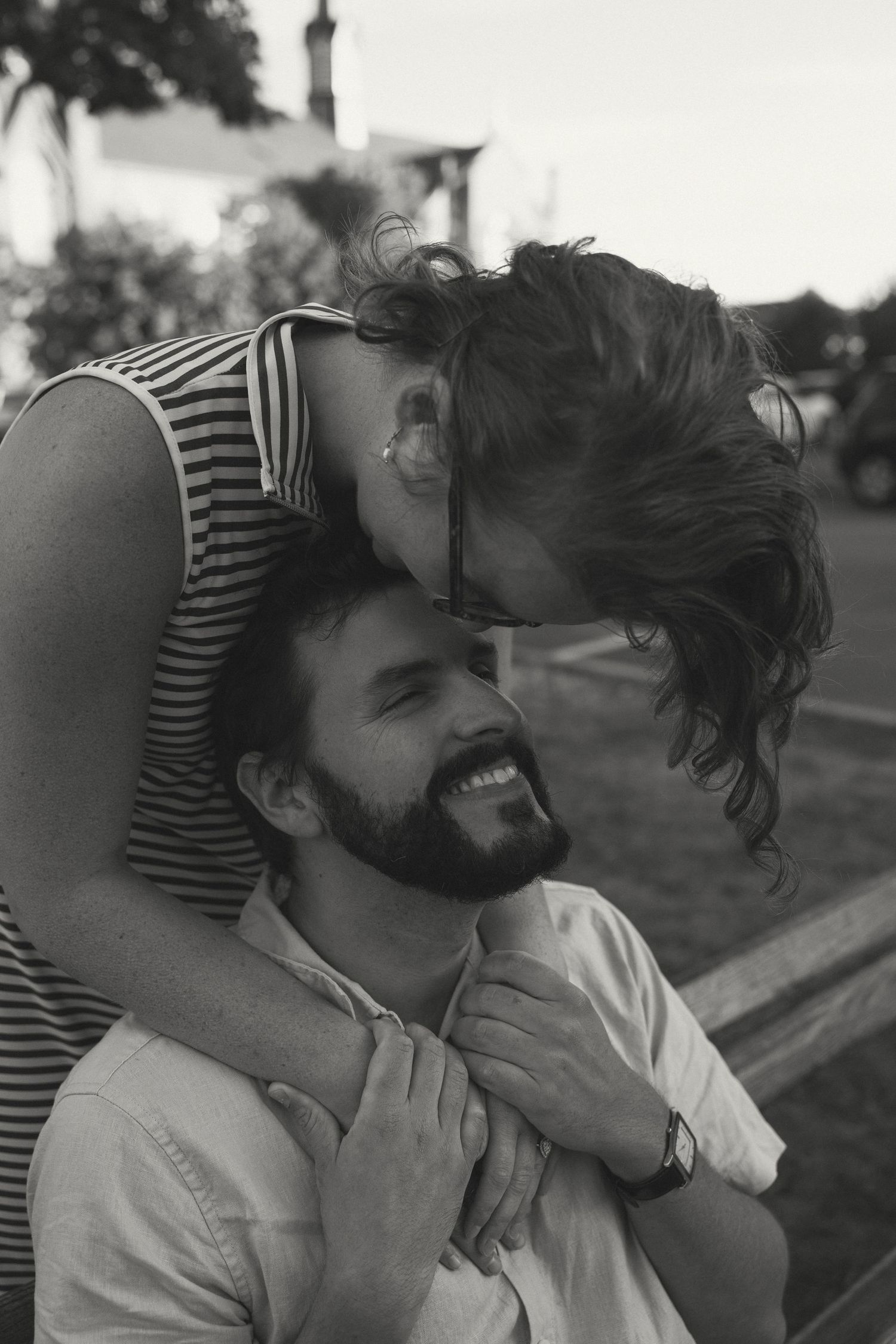 A playful black and white moment between two people on a bench.