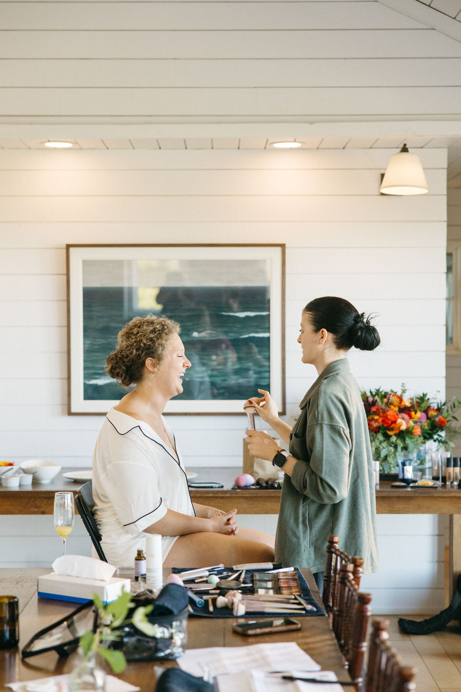 People preparing food in a bright modern kitchen with coastal artwork on the wall.