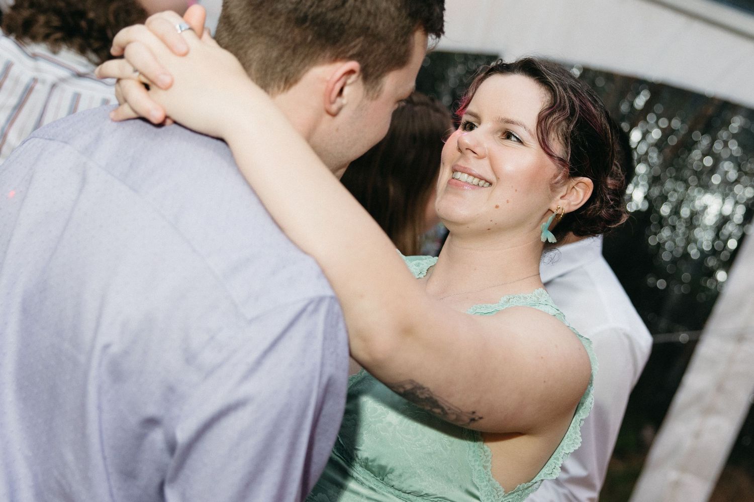 Woman in mint green dress smiling while dancing with partner at wedding reception.