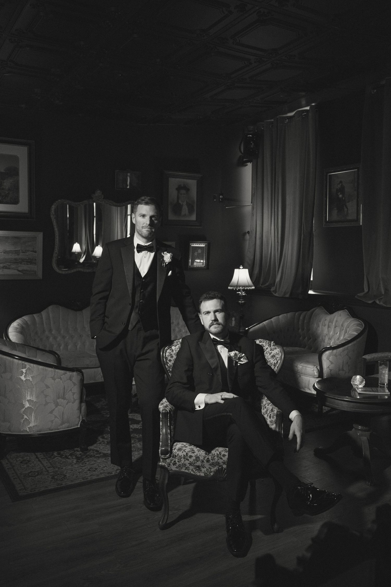 Artistic black and white photo of formal-dressed figures in a classic lounge setting.