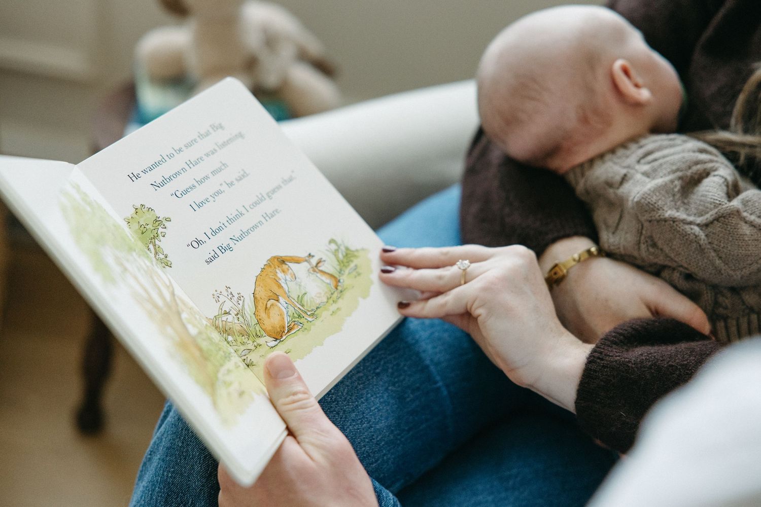 Two people reading a children's picture book together on a couch.