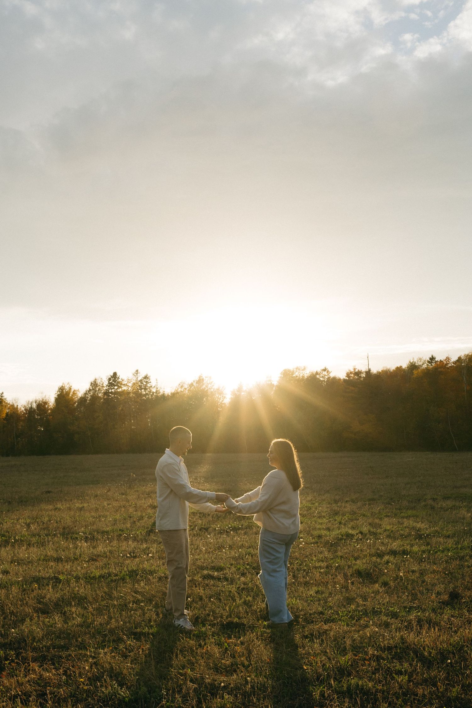 People sharing a tender moment in a field at golden hour.