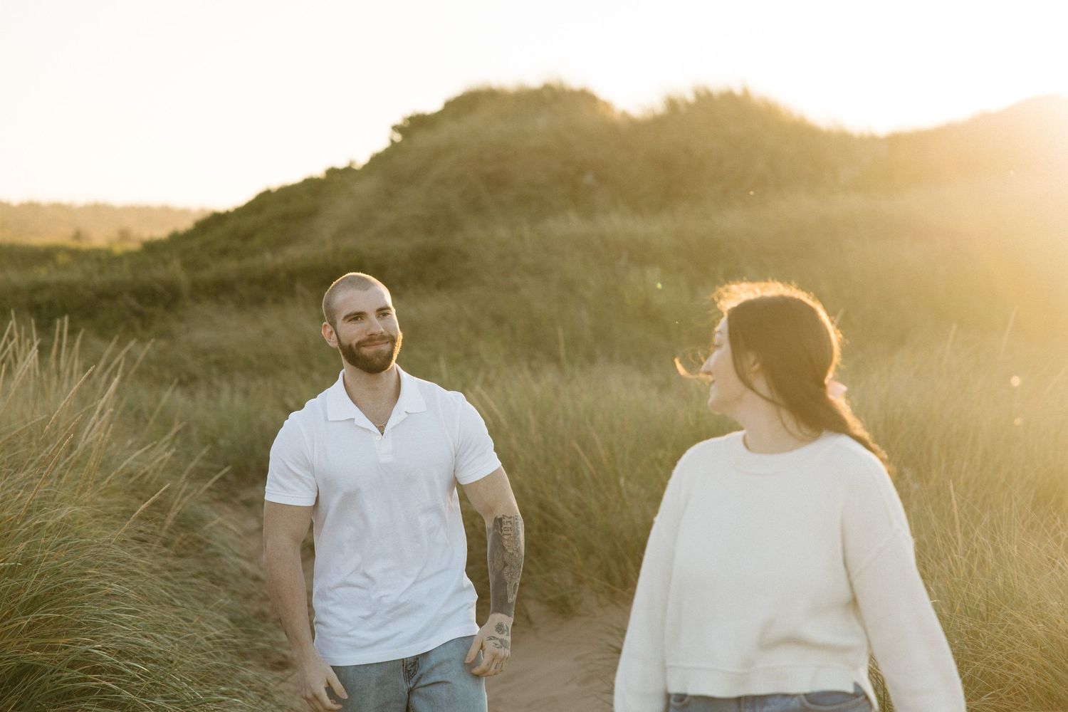 Couple sharing tender moment among sand dunes in evening light.