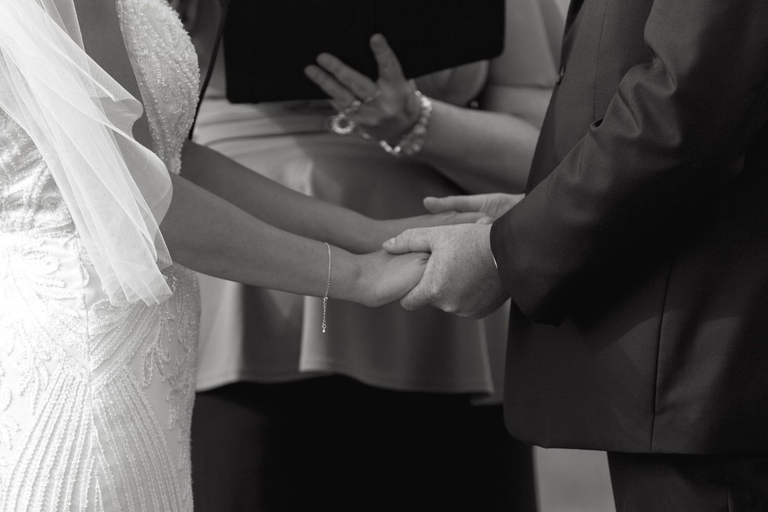 Close-up of hands during wedding ring exchange ceremony.