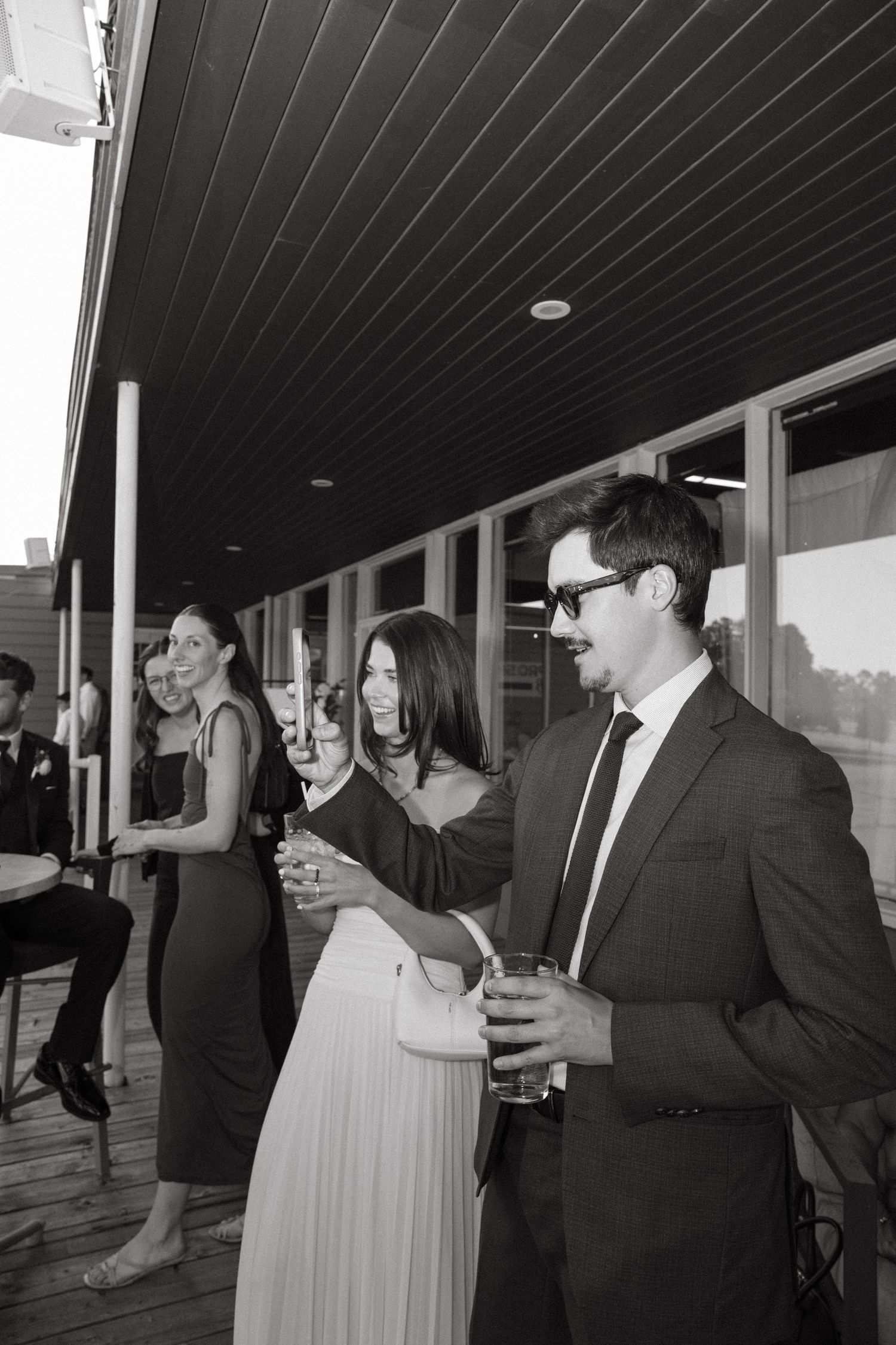 Wedding guests socializing under dark wooden ceiling during reception.