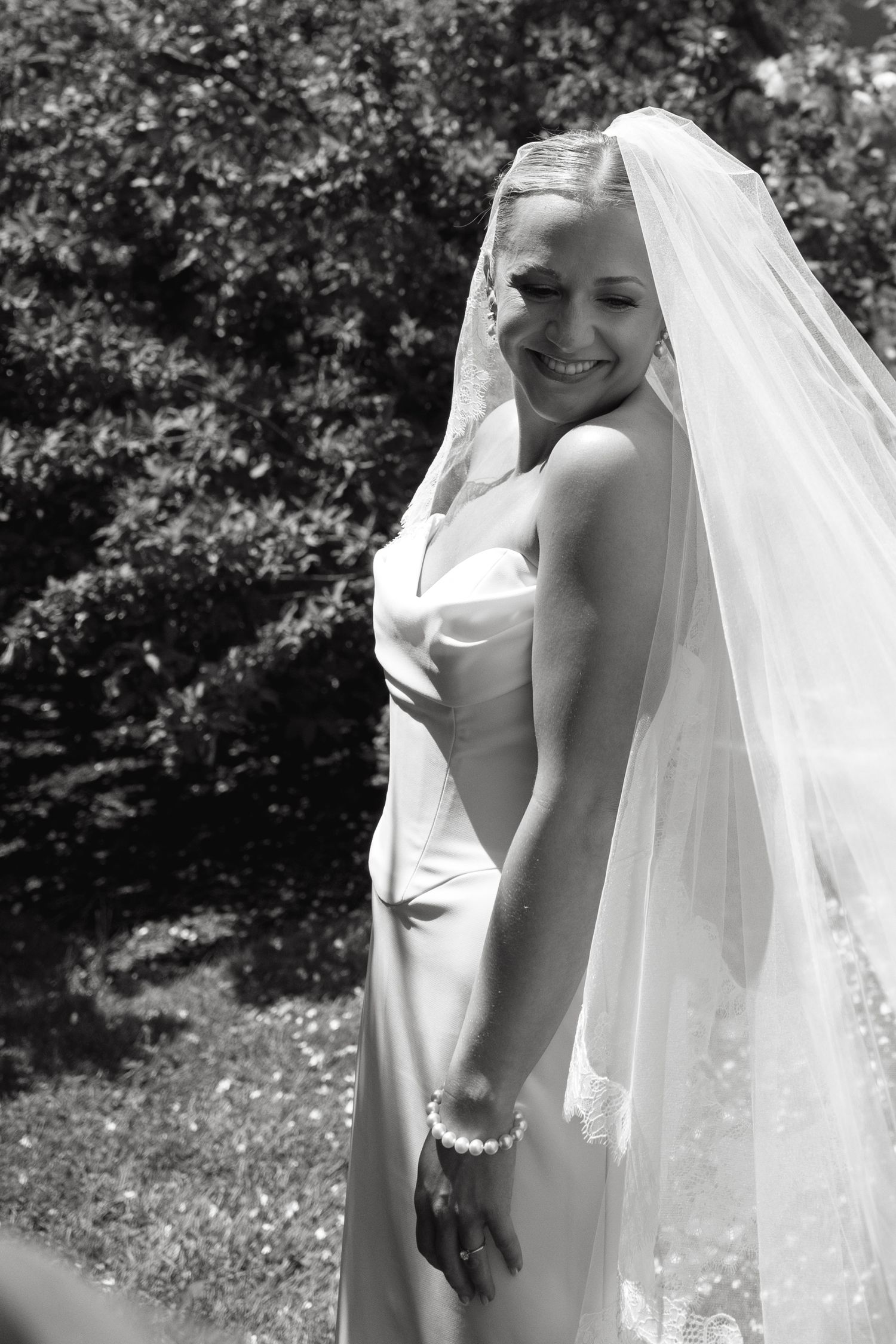 Black and white portrait of a bride in a flowing veil outdoors.