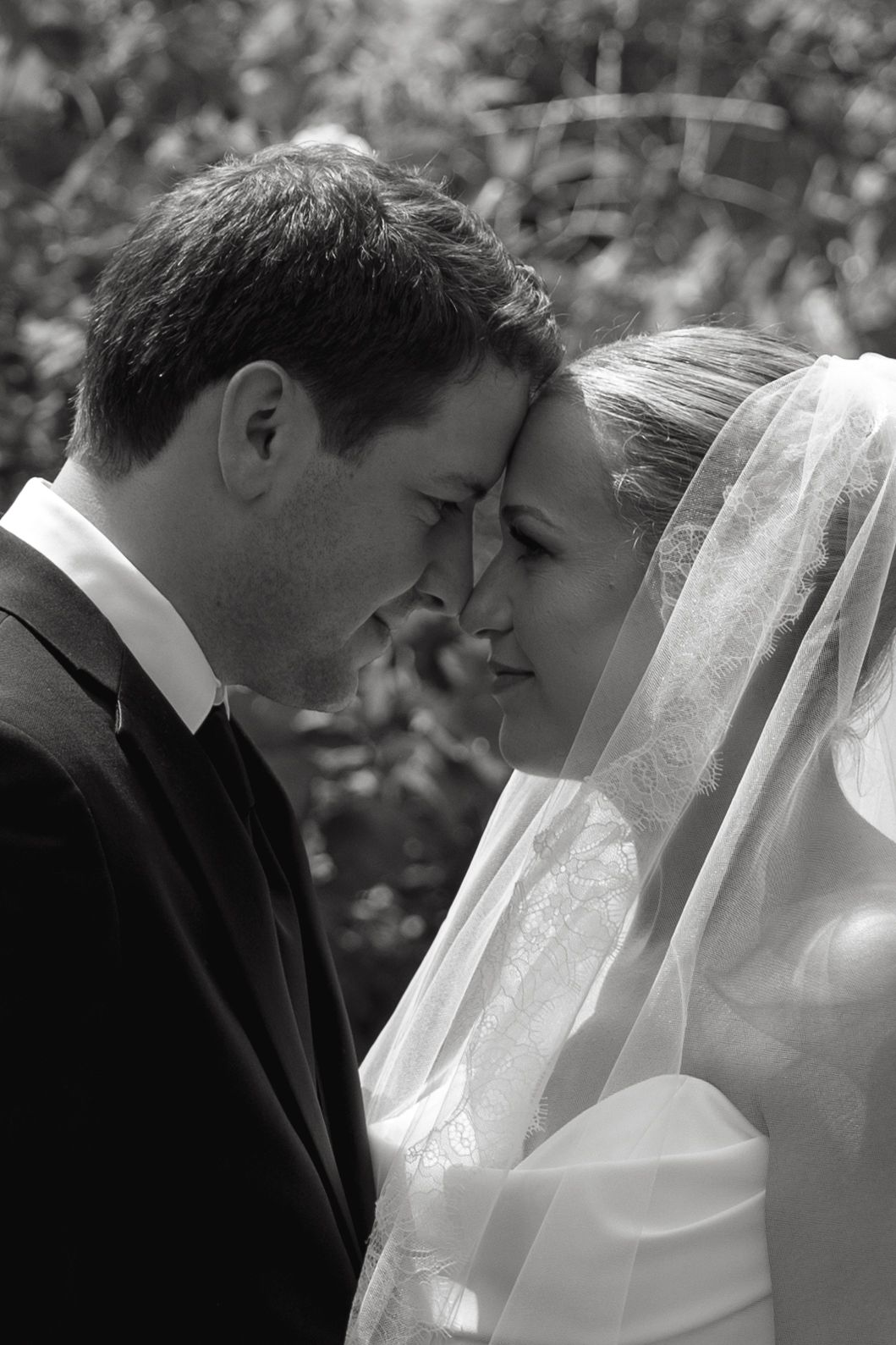 Intimate black and white portrait of a wedding couple in a garden setting.
