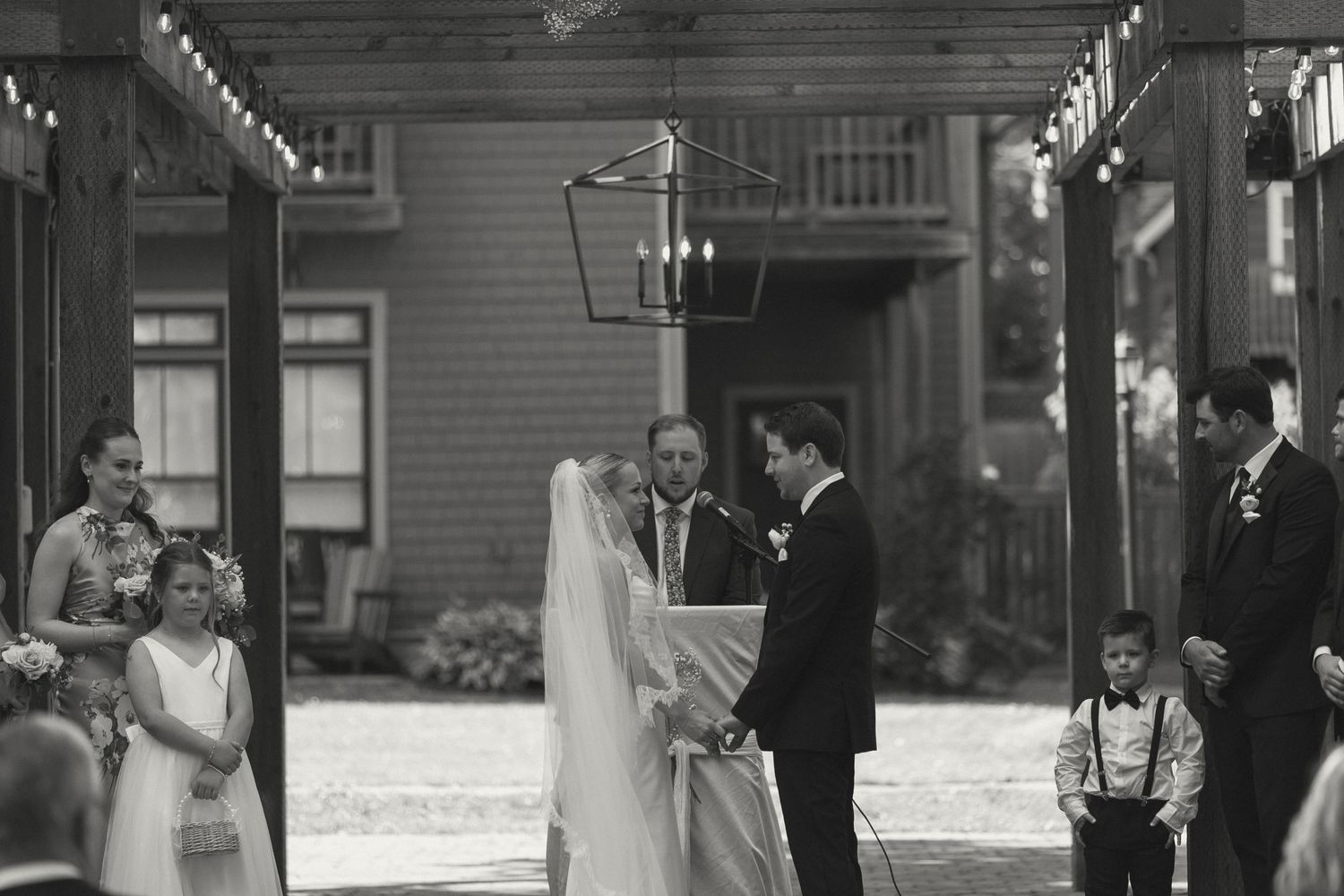 Outdoor wedding ceremony under a covered pavilion with guests seated.