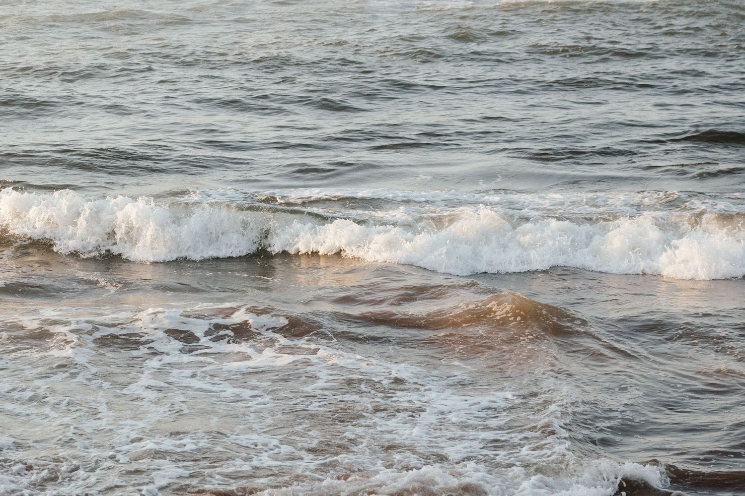 Ocean waves crash against the shore with white foam and blue water.