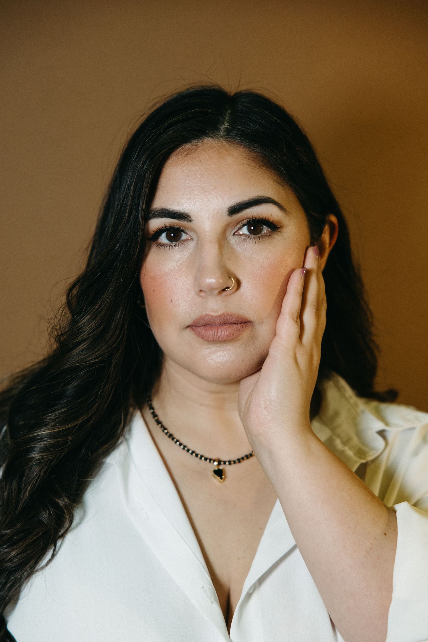 Portrait series showing different poses in a white shirt against a warm brown background.