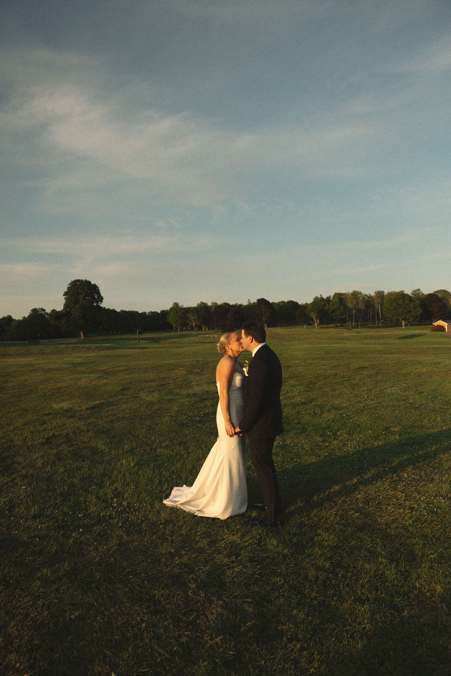 Couple shares an intimate moment at sunset on a golf course.