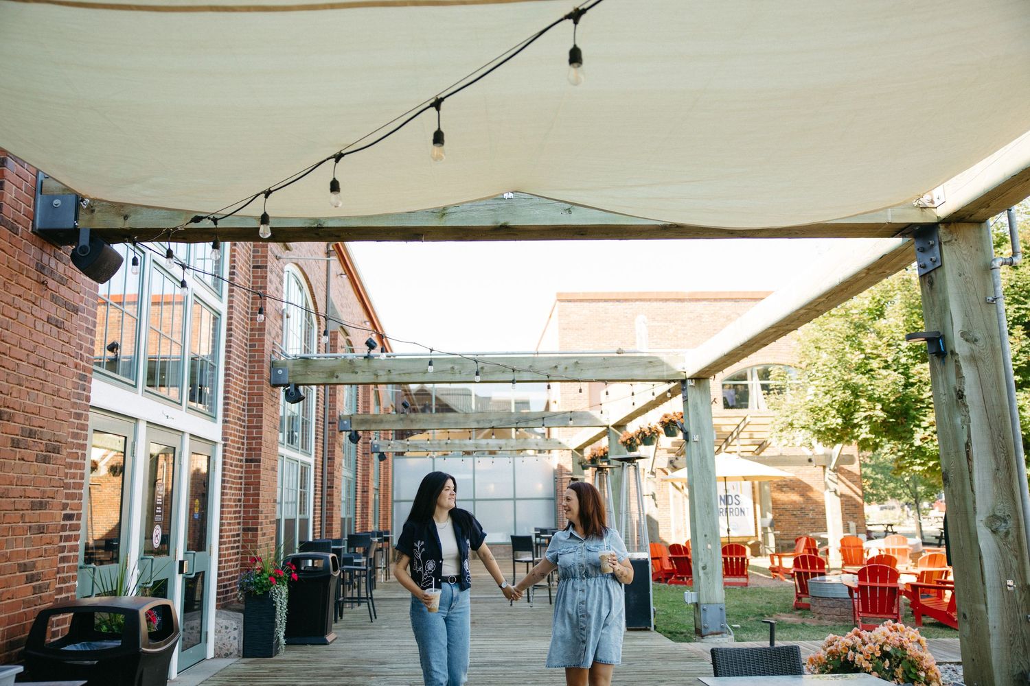 String lights hang above a covered outdoor seating area with brick walls and industrial styling.
