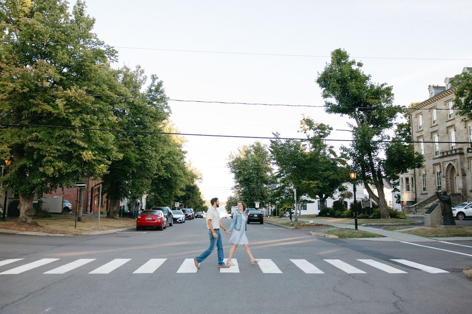 A quiet residential street intersection with crosswalks and trees.