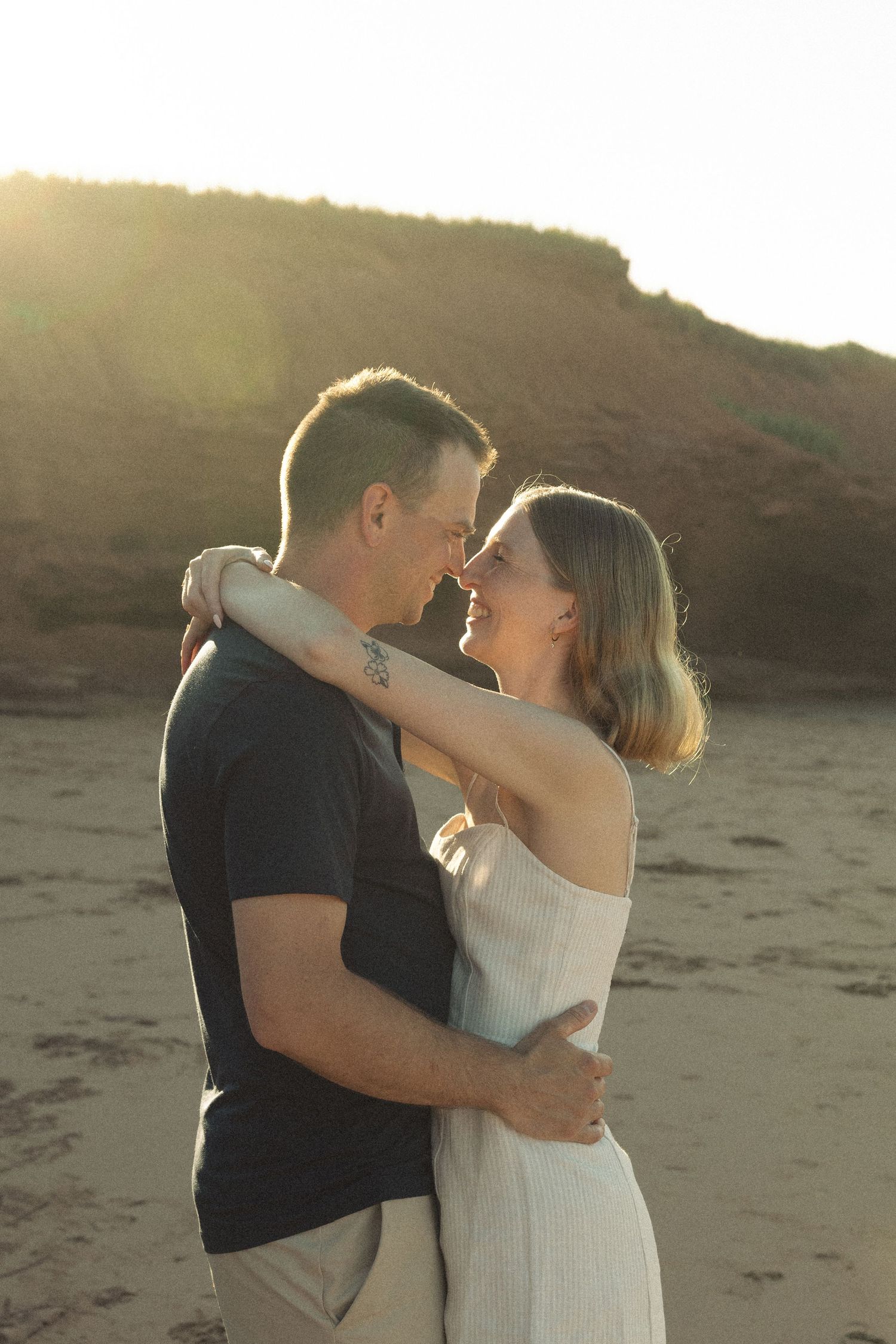 A tender embrace between a couple on a beach at golden hour.