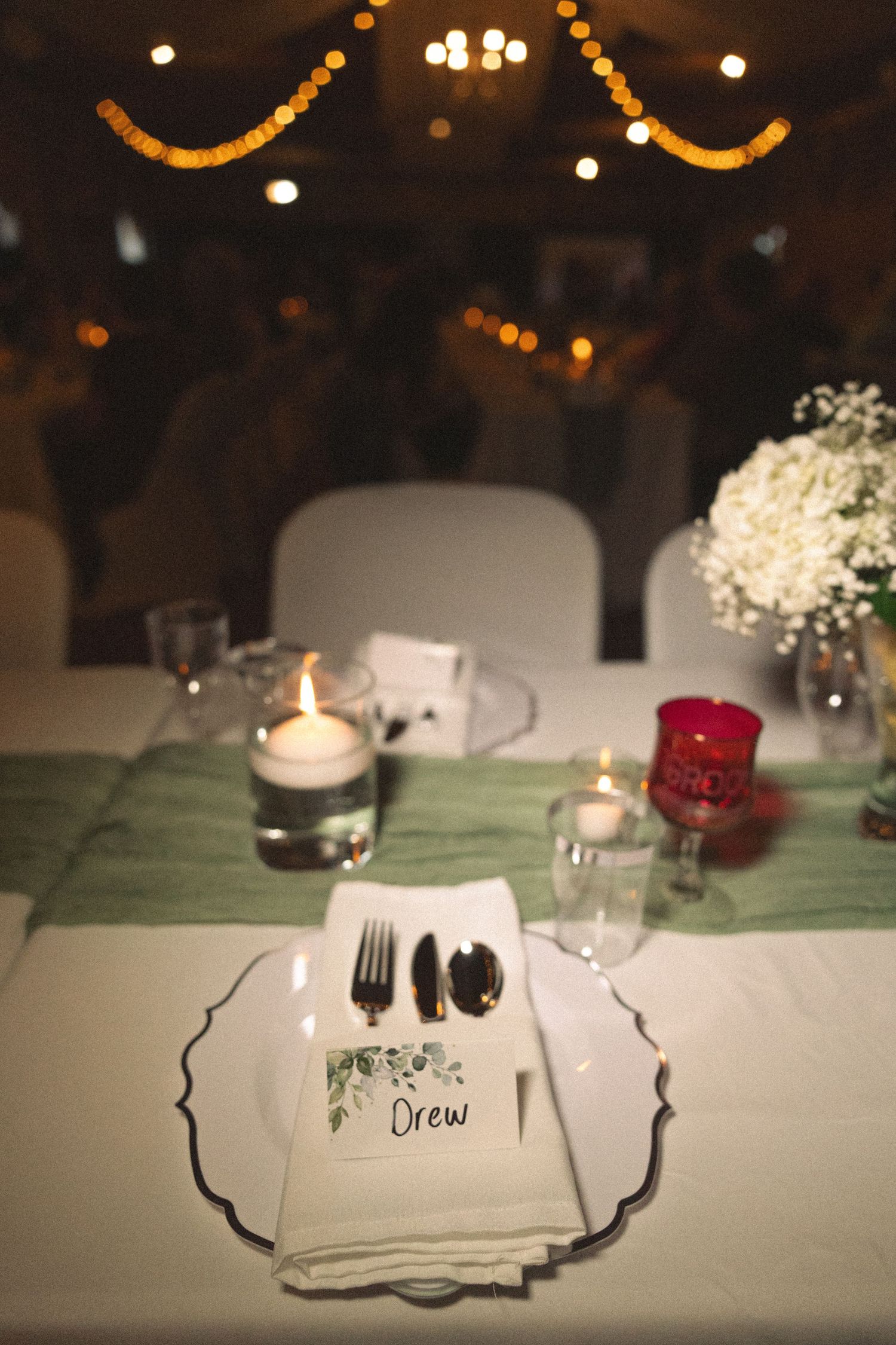 An elegant place setting with candles, name card, and baby's breath centerpiece.