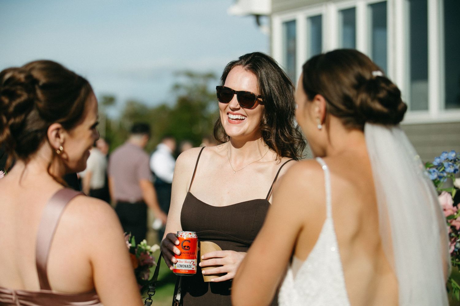 Wedding party members holding drinks during outdoor celebration.