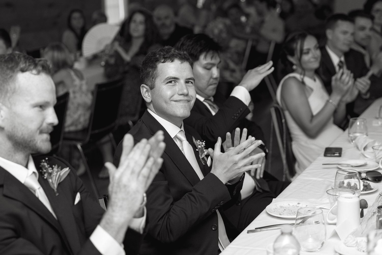 Wedding guests applauding during reception celebration.