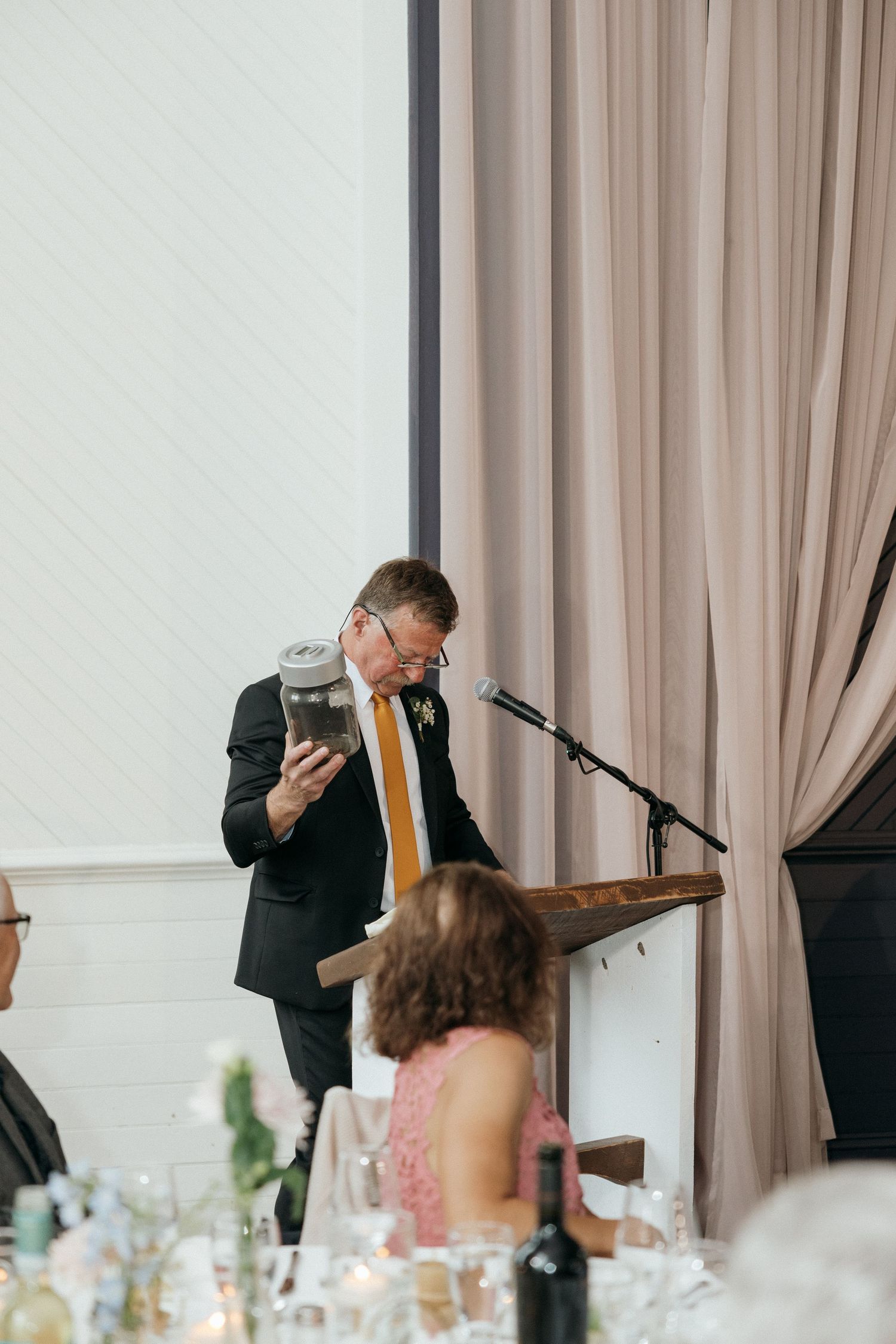 Speaker delivers emotional wedding toast at elegant indoor reception.
