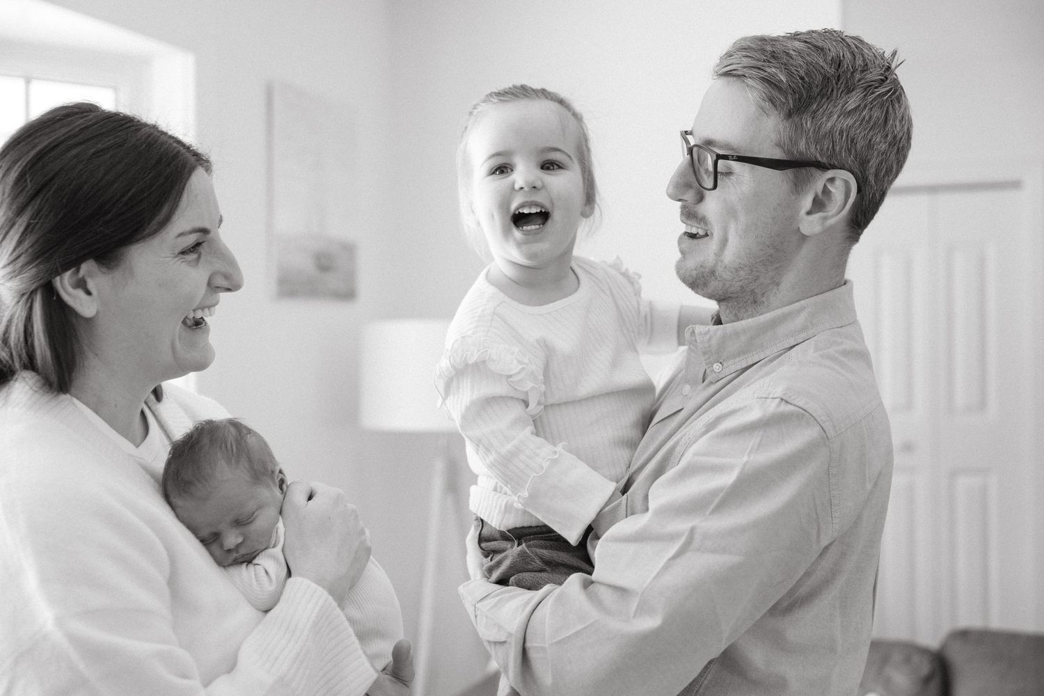 Black and white series showing joyful family moments in bright interior setting.