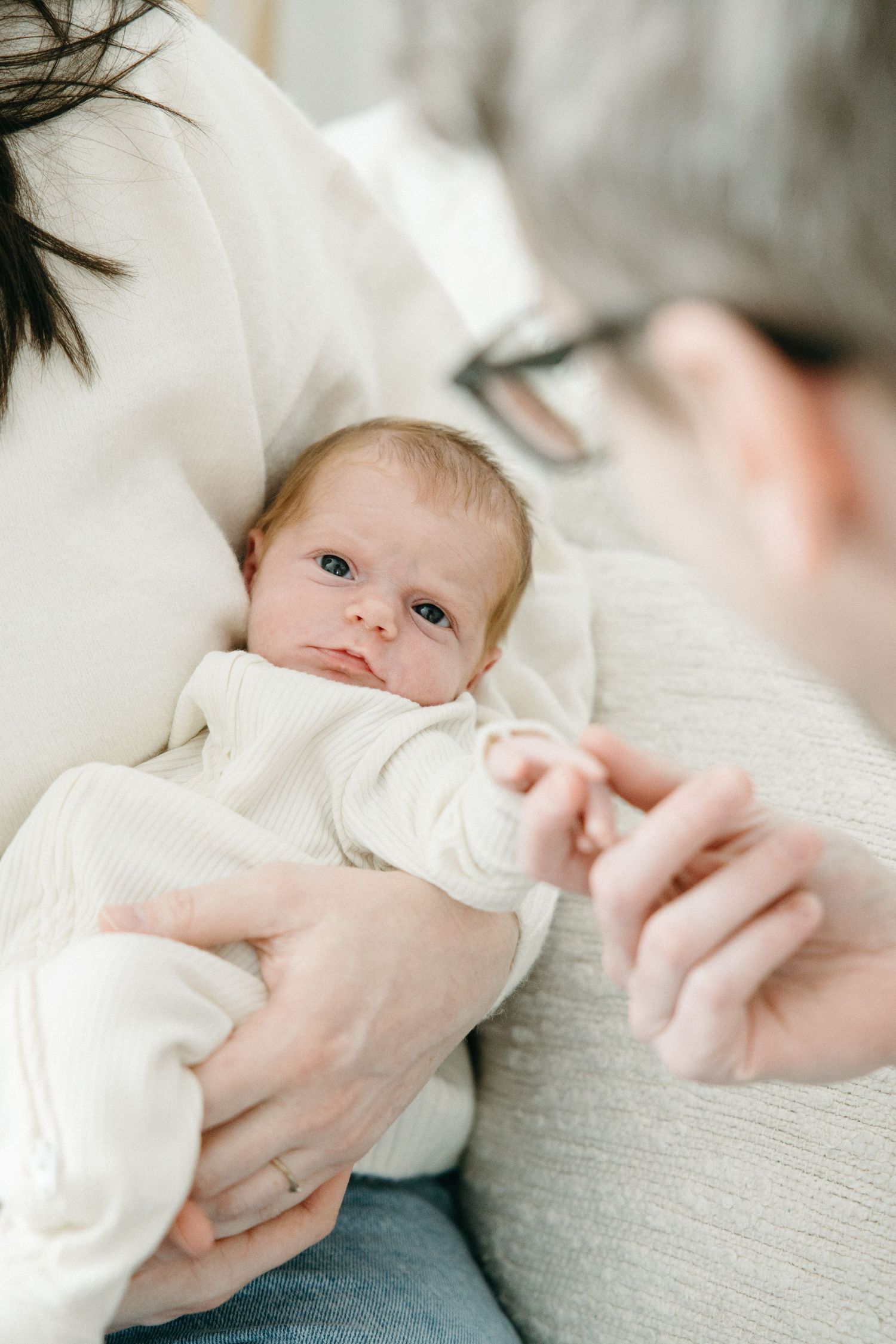 Close-up series of a baby in white clothing being cradled gently.
