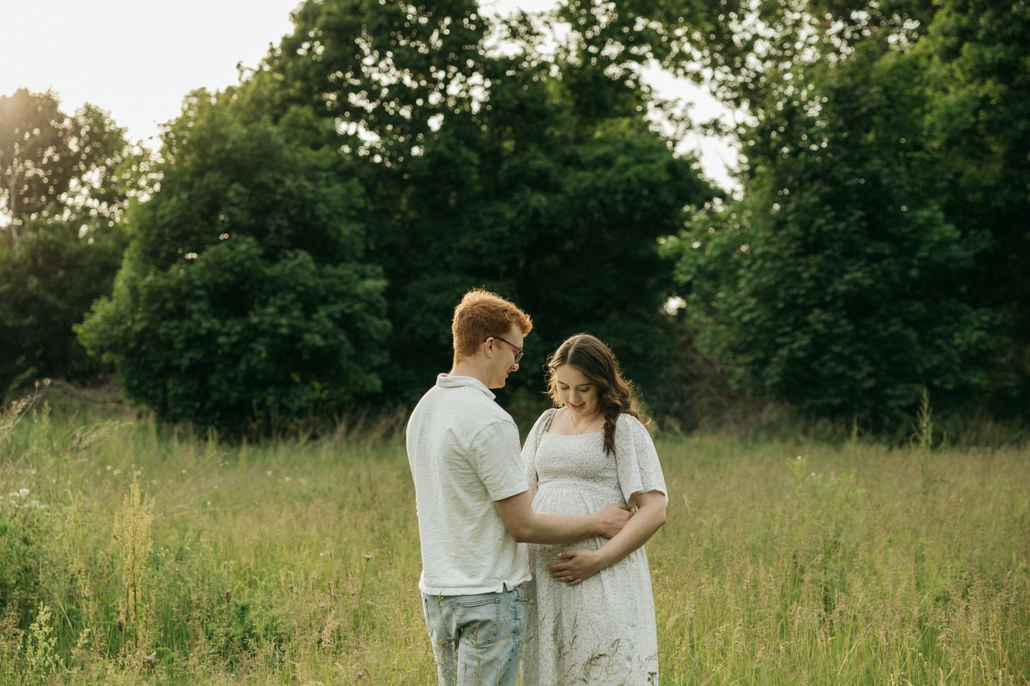 Romantic scene of a couple dancing together in a peaceful meadow with natural lighting and green foliage.